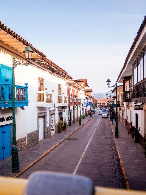 A narrow, cobblestone street flanked by colorful, colonial-style buildings with balconies, under a clear blue sky.