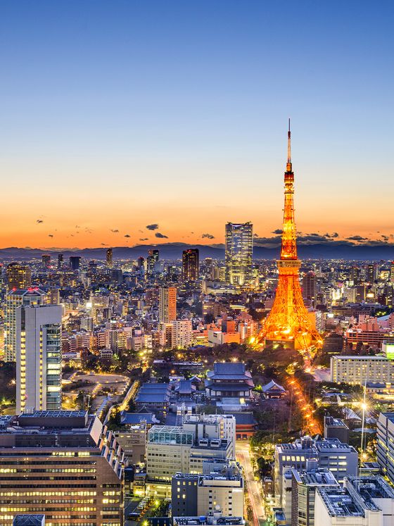 Tokyo skyline at dusk featuring the illuminated Tokyo Tower, with a vibrant orange sunset in the background.
