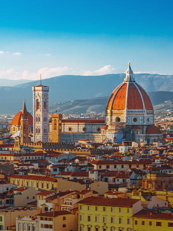 Aerial view of Florence, Italy, featuring the Cathedral of Santa Maria del Fiore with its iconic red dome and the surrounding historic buildings.