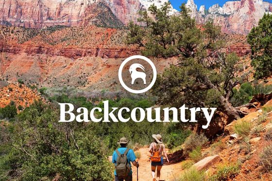 Two hikers on a scenic trail with red rock formations and blue sky, featuring the word "Backcountry" and a mountain goat logo at the center.