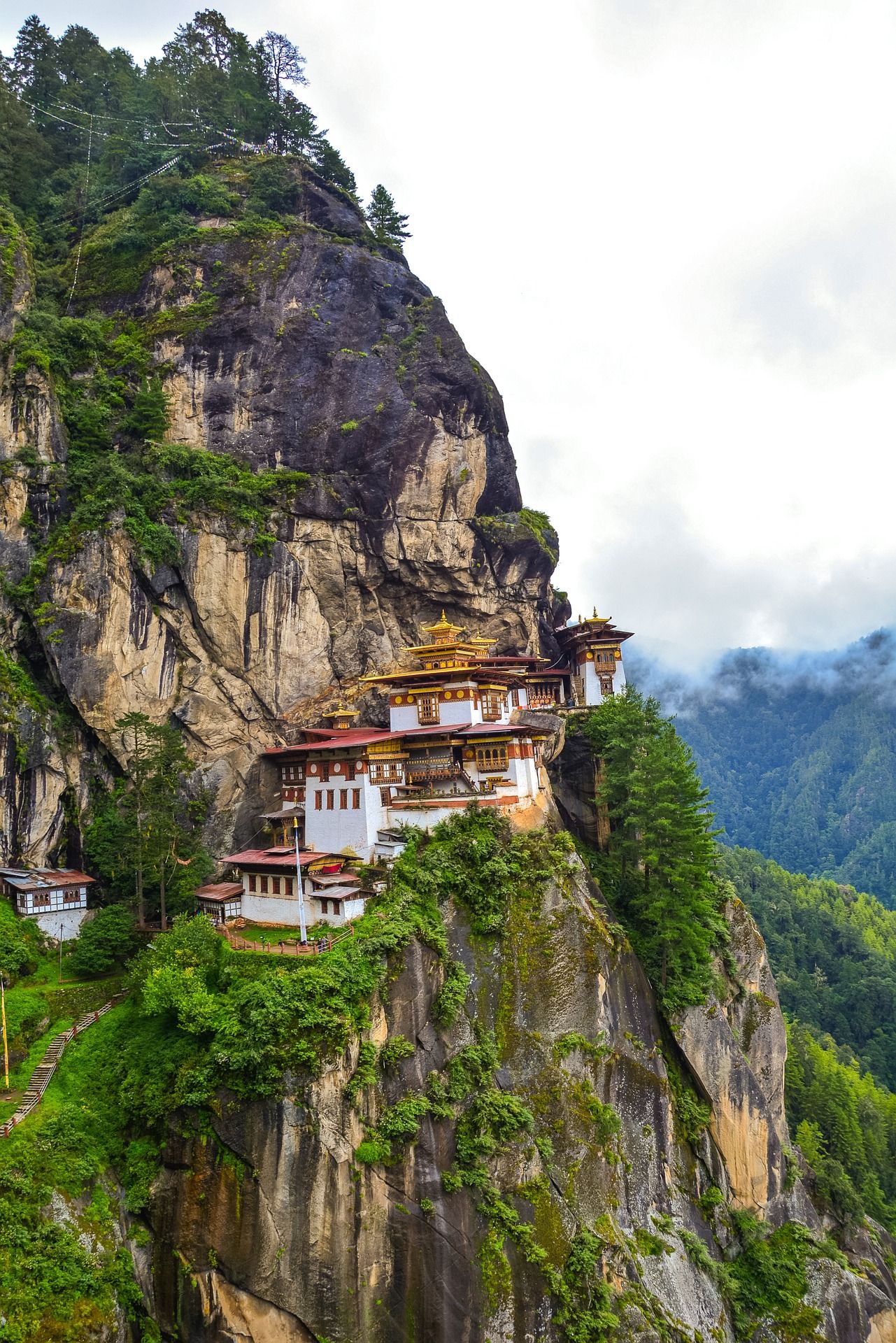 Tiger's Nest Monastery perched on a cliffside, surrounded by lush greenery and misty mountains in Bhutan.