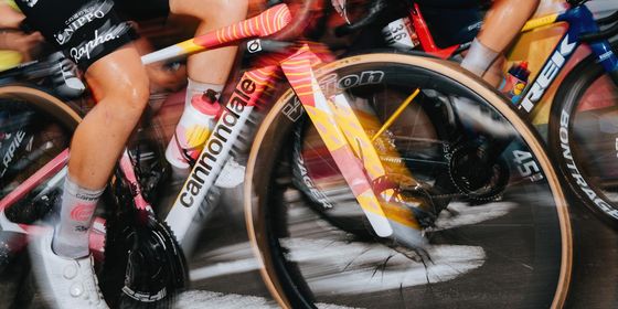 Cyclists in motion during a race, wearing colorful jerseys and helmets, with a blurred background conveying speed and intensity.