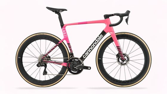 Pink and black Cannondale aero road bike in profile with deep-section carbon wheels and tan-wall tires on a white background.