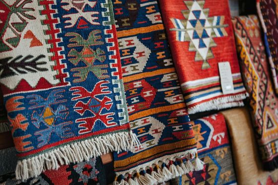 Colorful woven tapestries hanging in a row, featuring intricate geometric patterns and tribal designs in red, blue, and yellow hues.