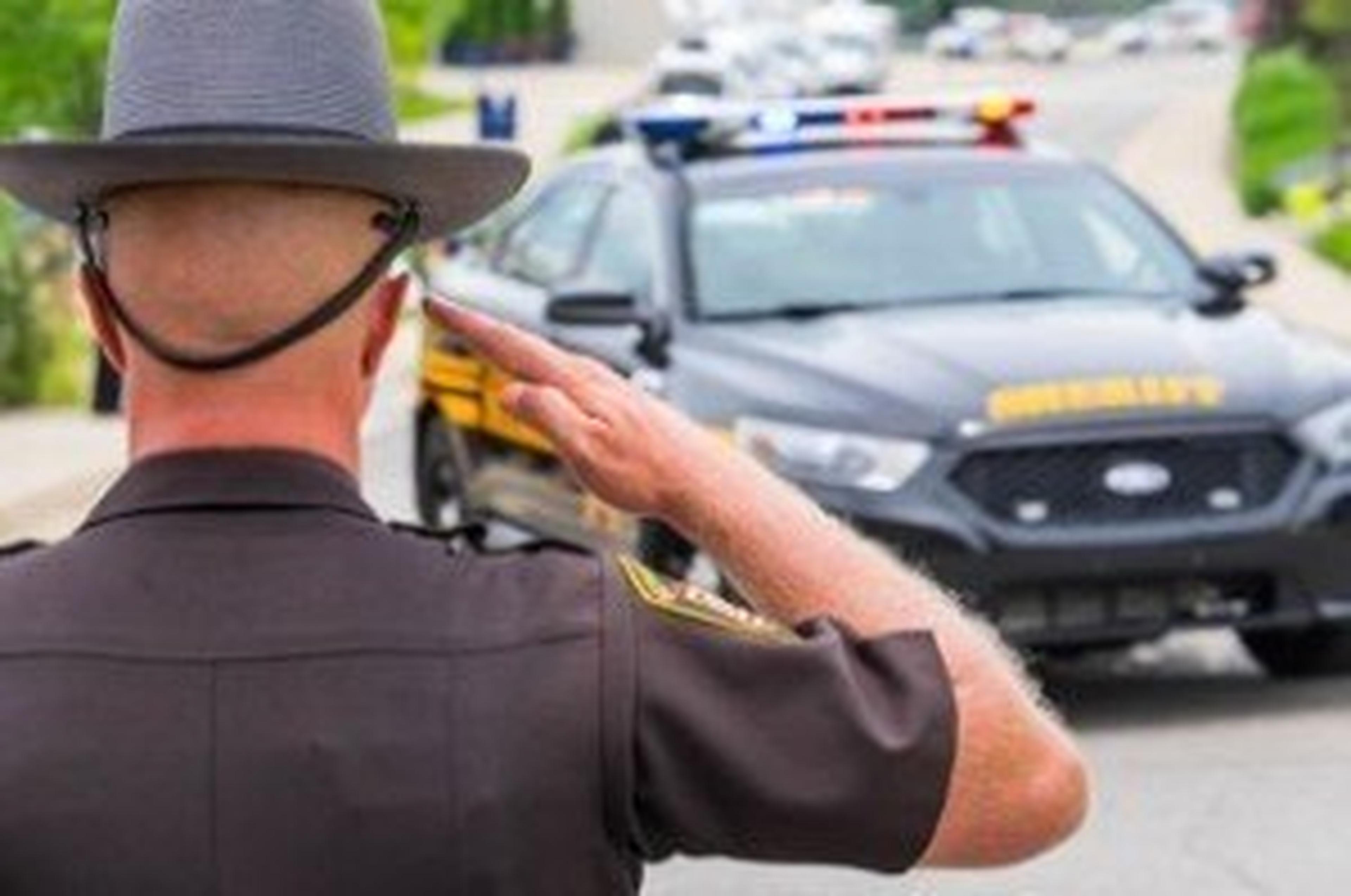 Police officer saluting a police vehicle in traffic