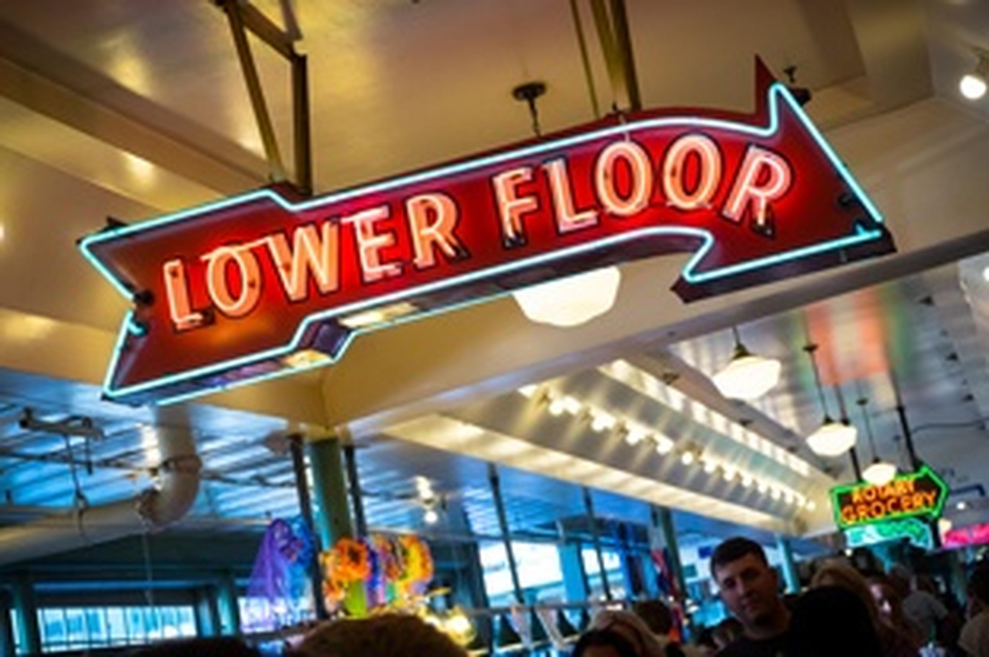 neon sign in the shape of an arrow reading lower floor