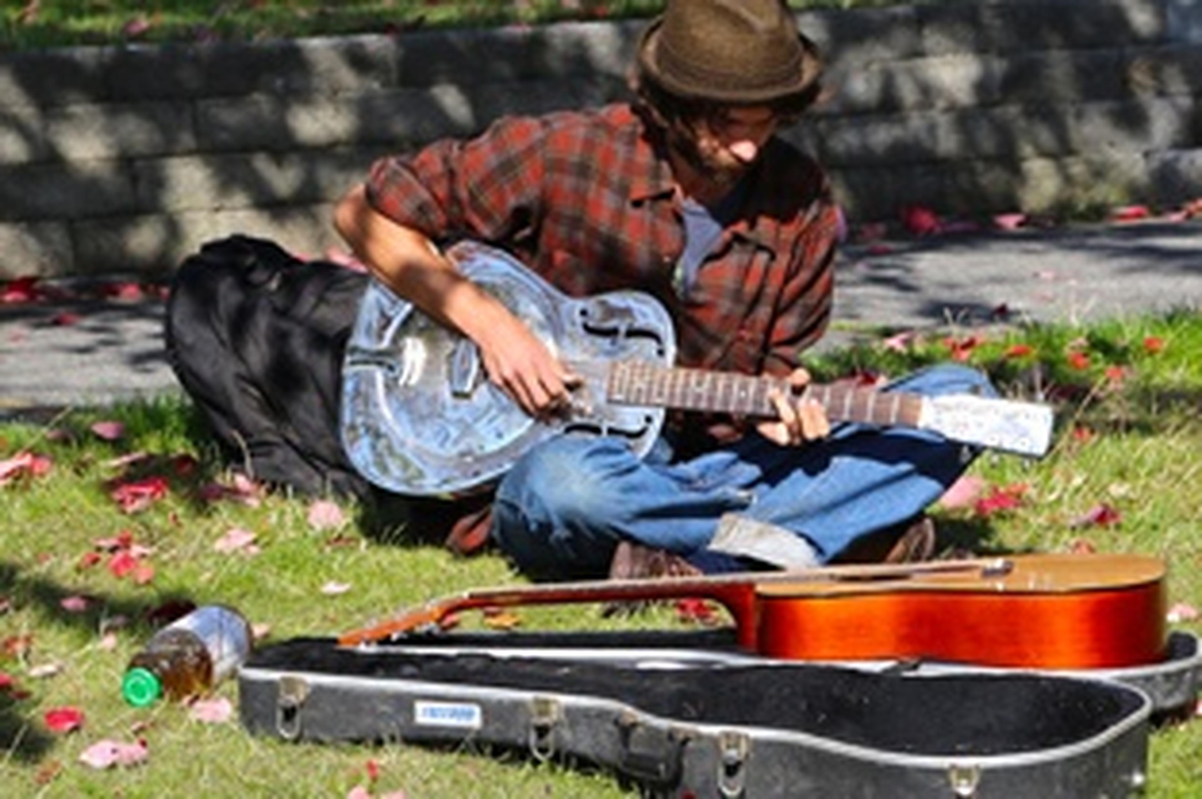 man playing guitar in the grass