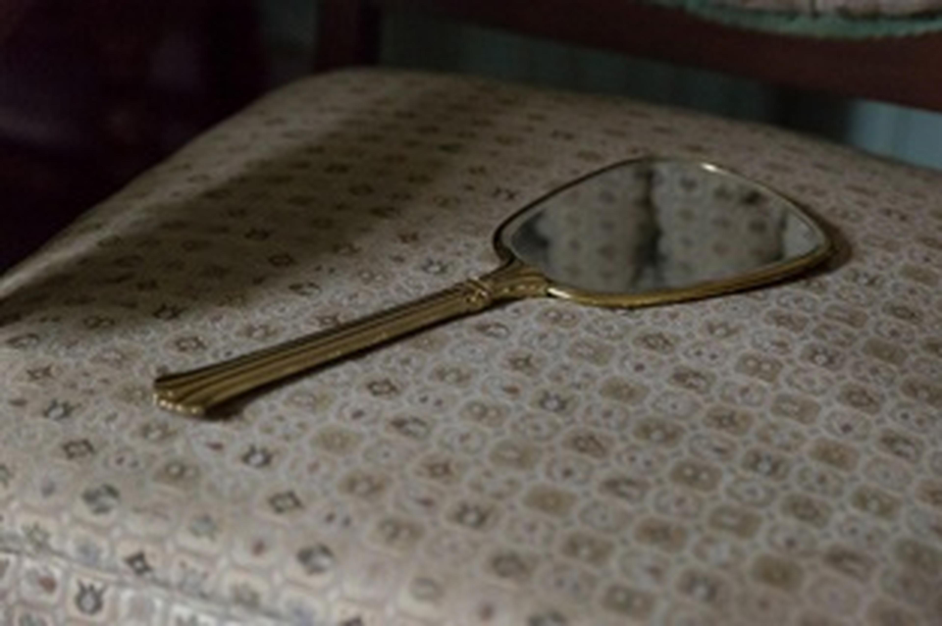 handheld mirror lying on seat of upholstered chair