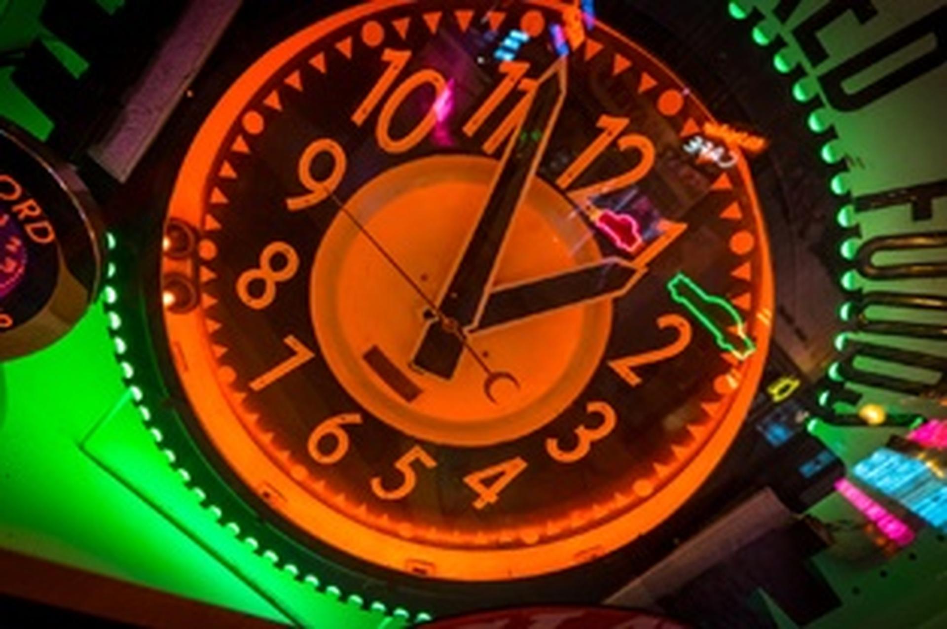 neon orange and black clock with green lights behind it