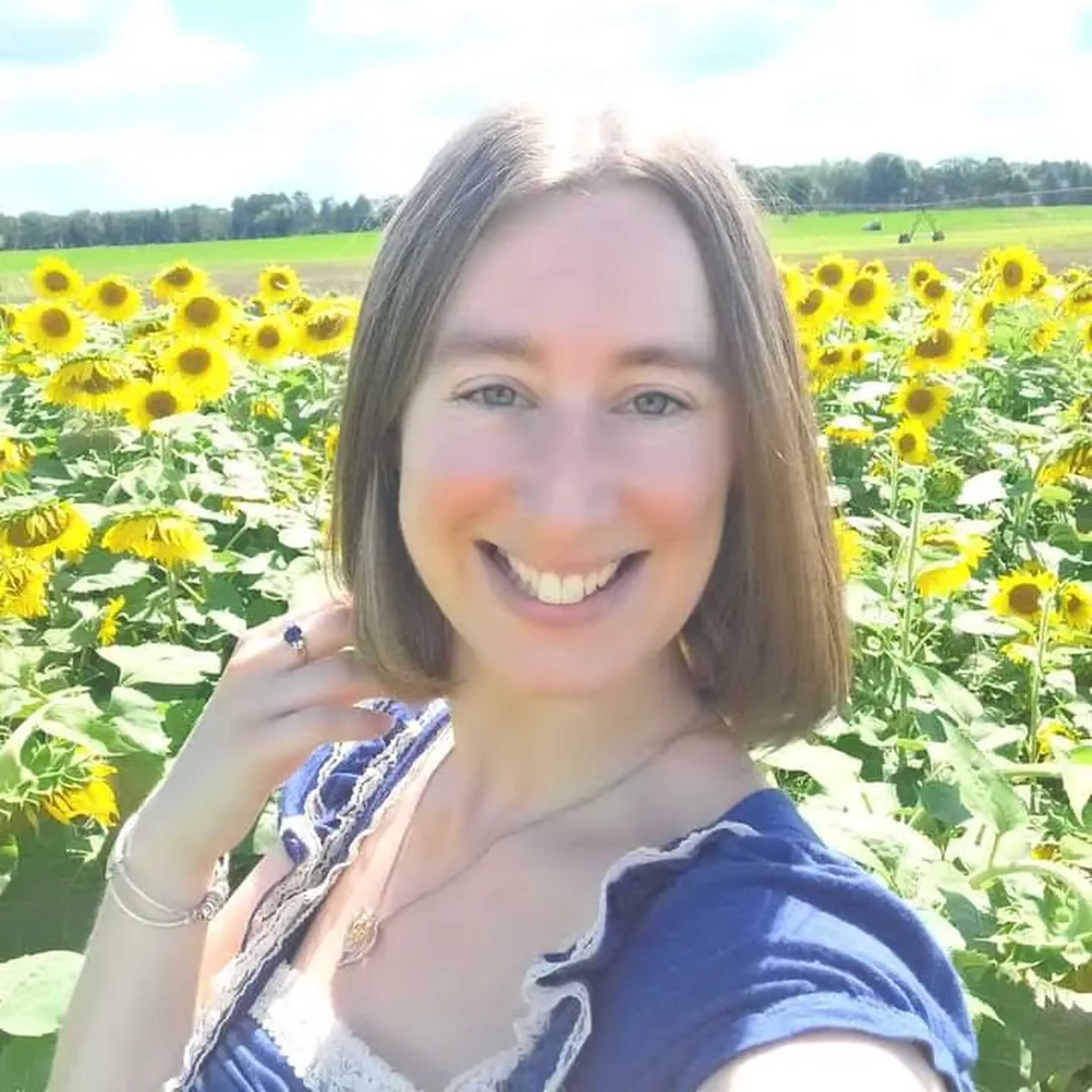 An image of Shanna DeBoer standing in front of a field of sunflowers