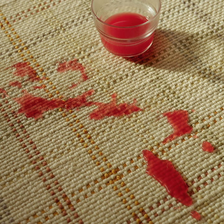 close up of red juice spilled on top of rug 