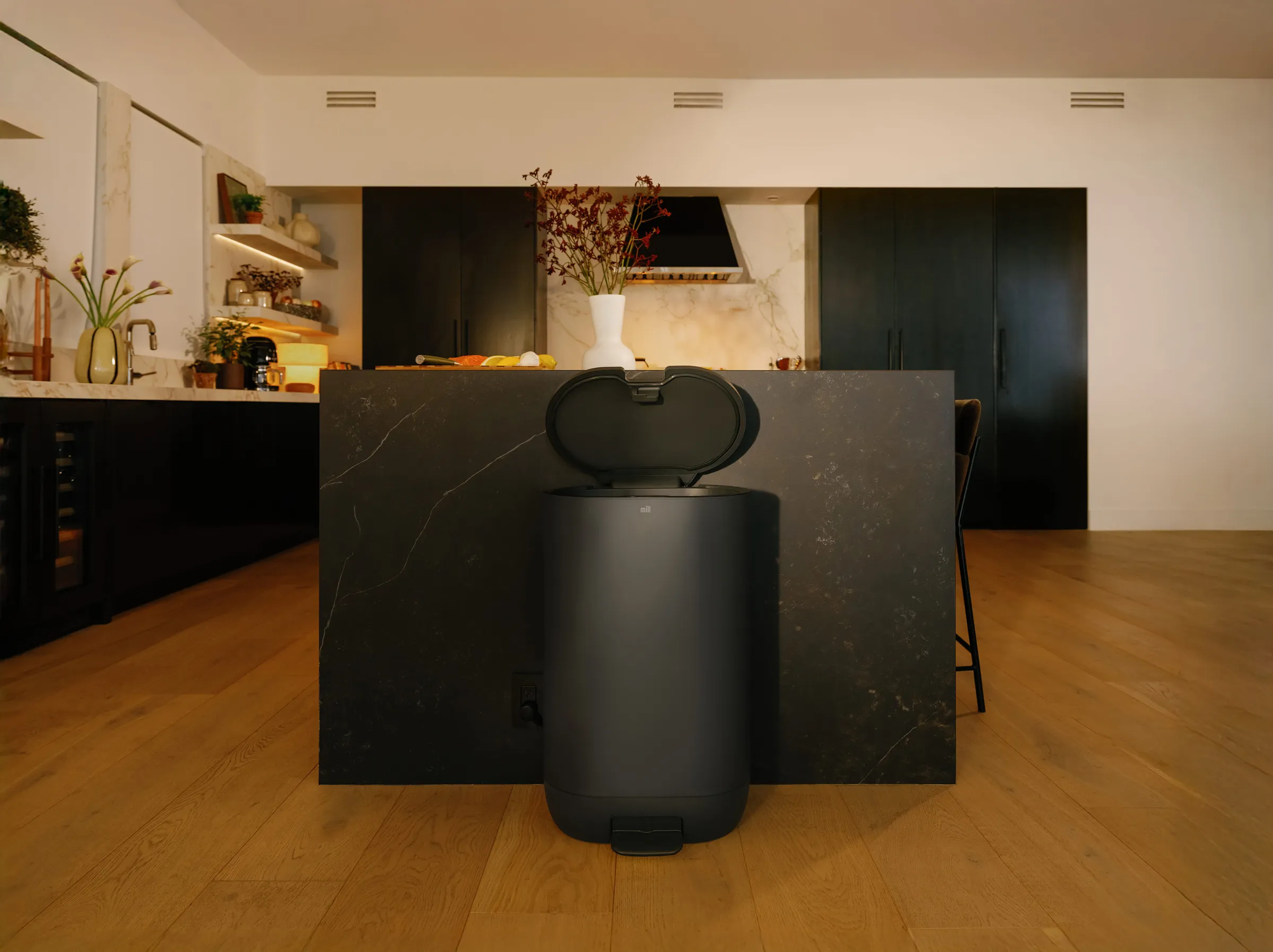 A Mill bin with its lid open, lit against a dark kitchen