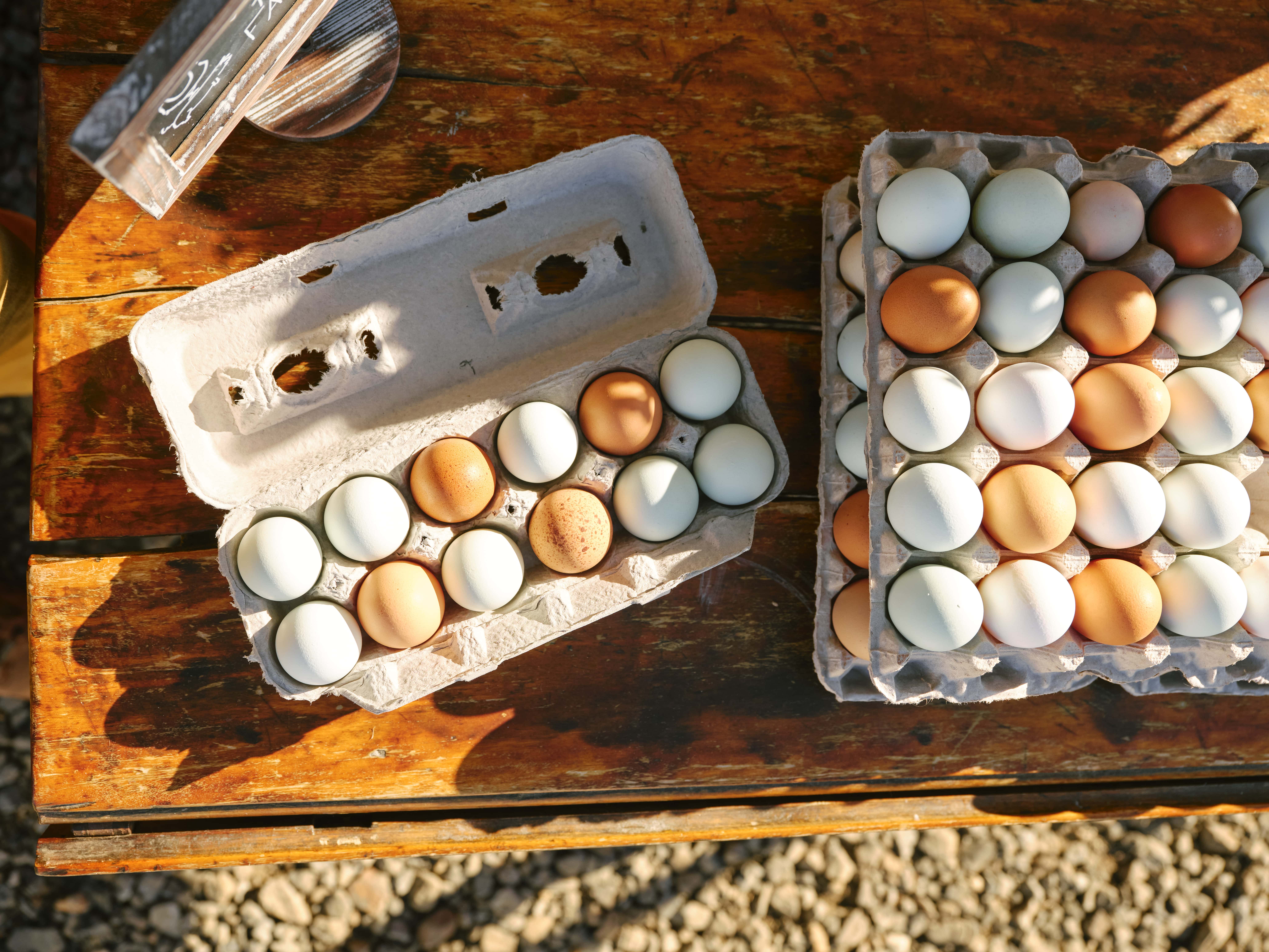 A rustic overhead view of eggs in cardboard cartons on a wooden surface