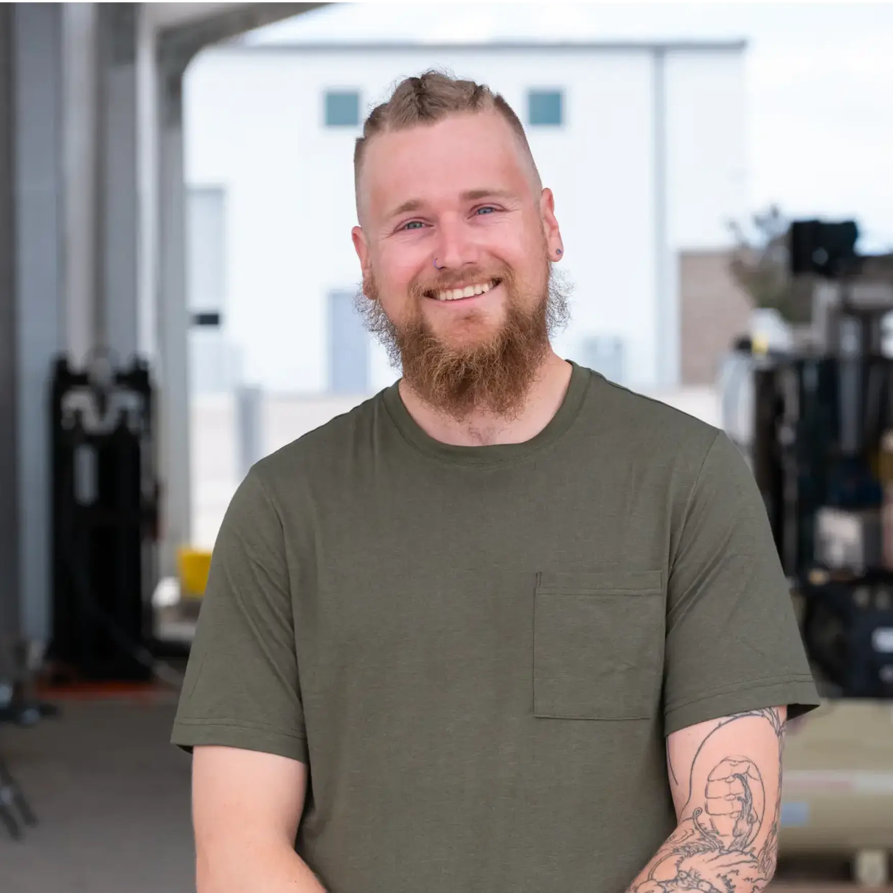 Portrait of Adam, a Charm Industrial operator, standing in the company facility wearing a green t-shirt