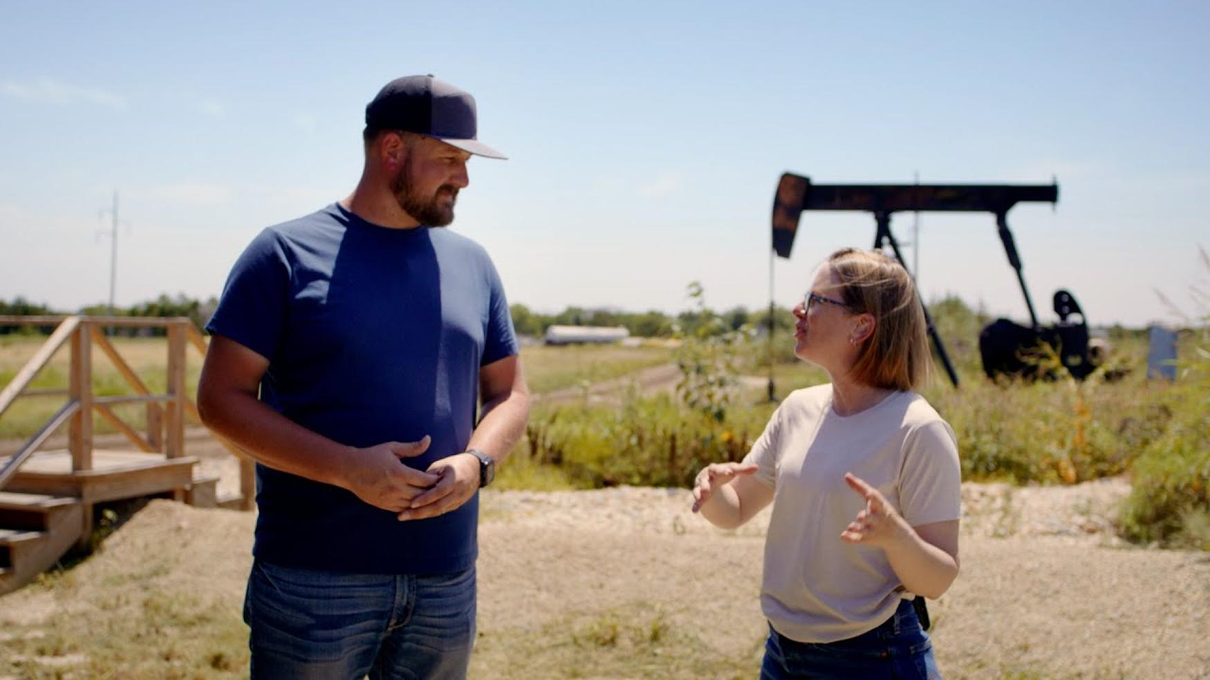 Caleb, Field Injection Operations specialist, talking with a team member at a carbon injection site with drilling equipment visible in the background