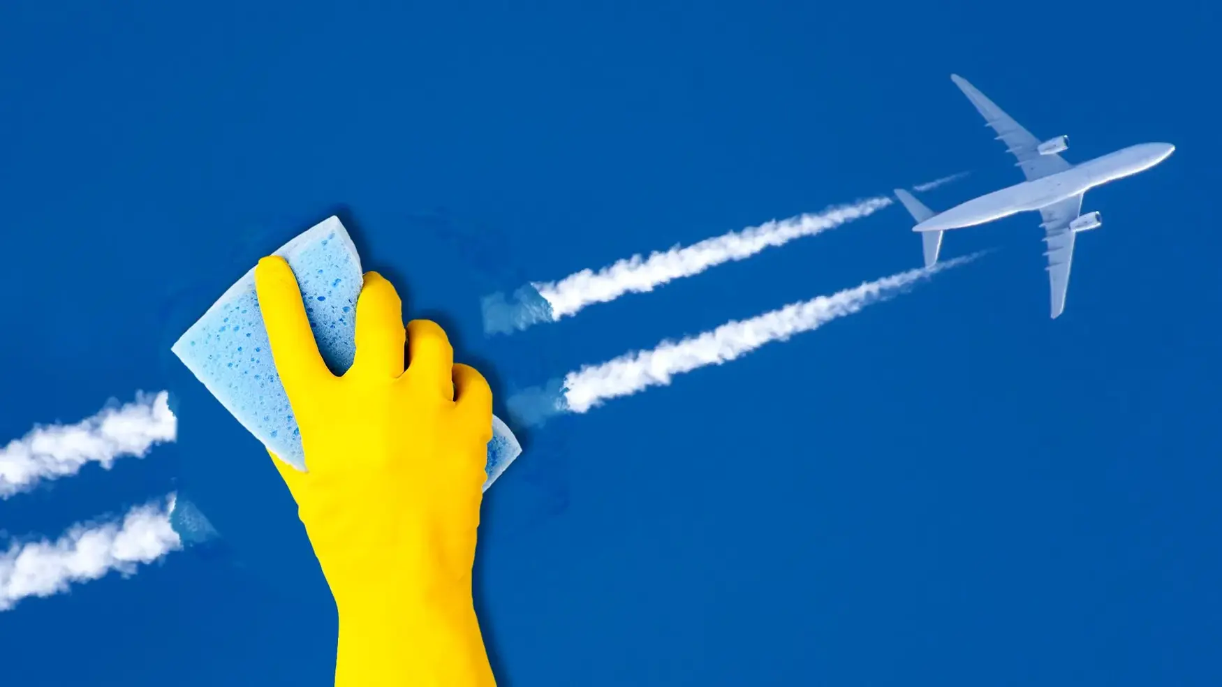 A yellow-gloved hand with a sponge appears to wipe away contrails behind a flying airplane in a clear blue sky.