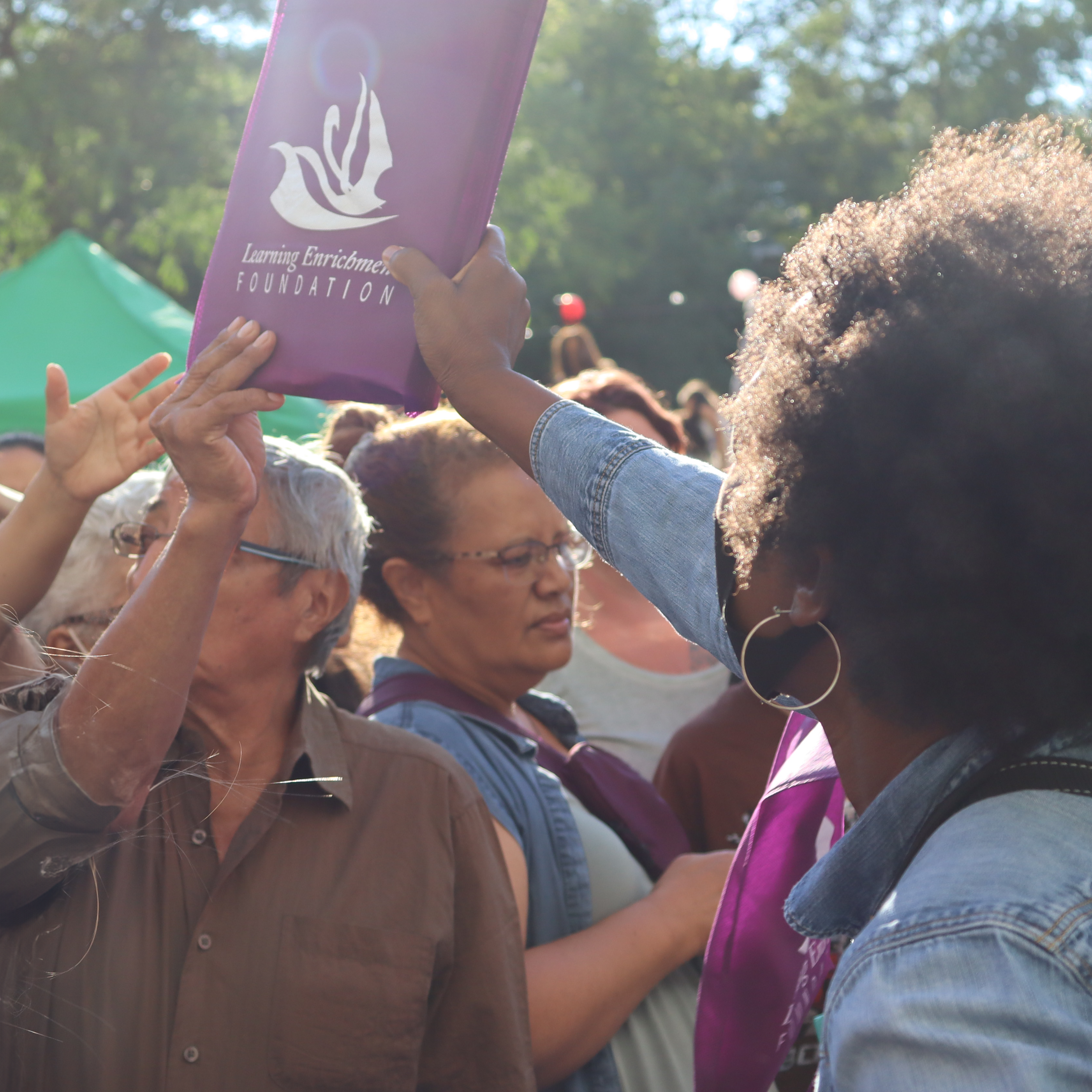 A woman handing out a LEF bag to a crowd of people.