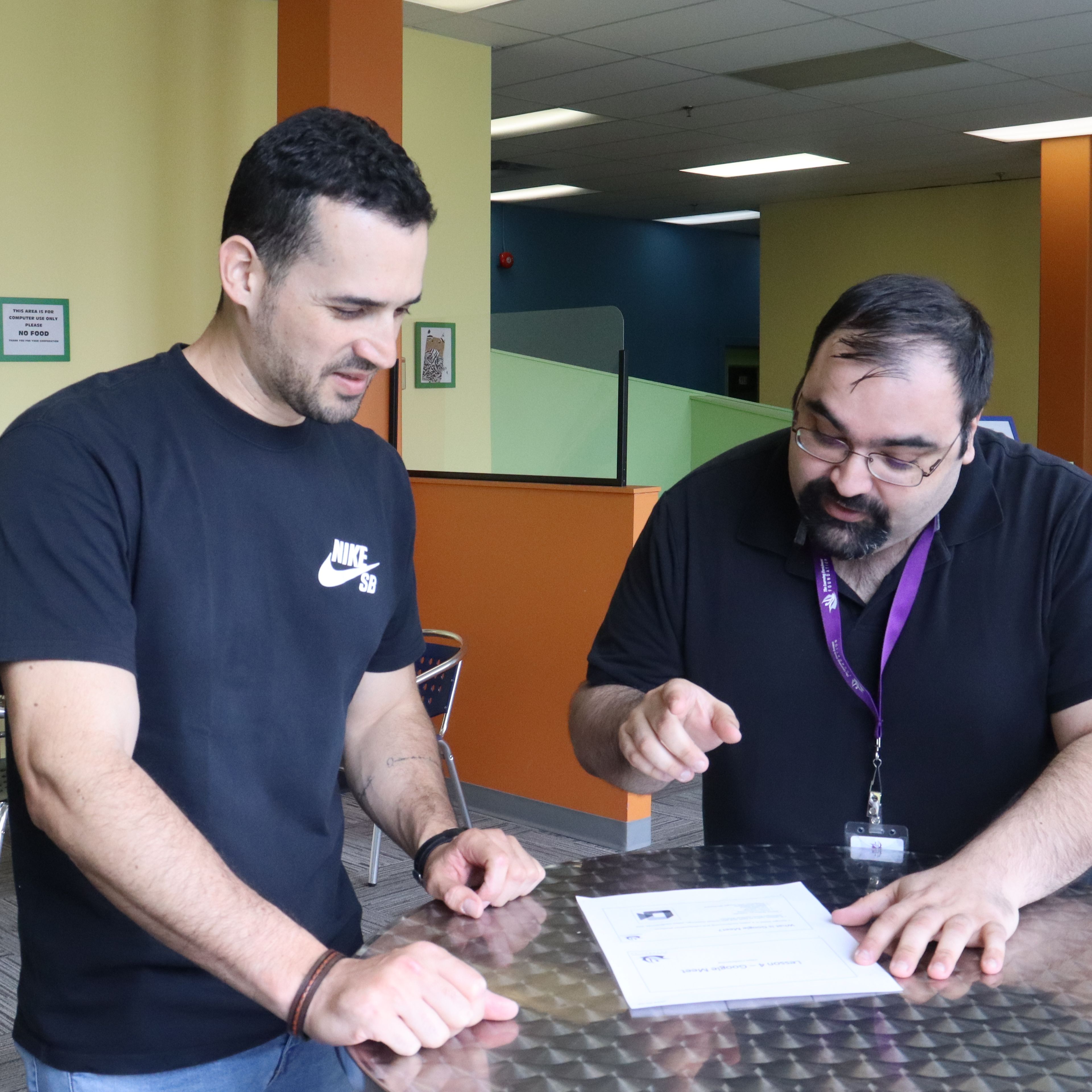 Two people standing up and talking at a table.