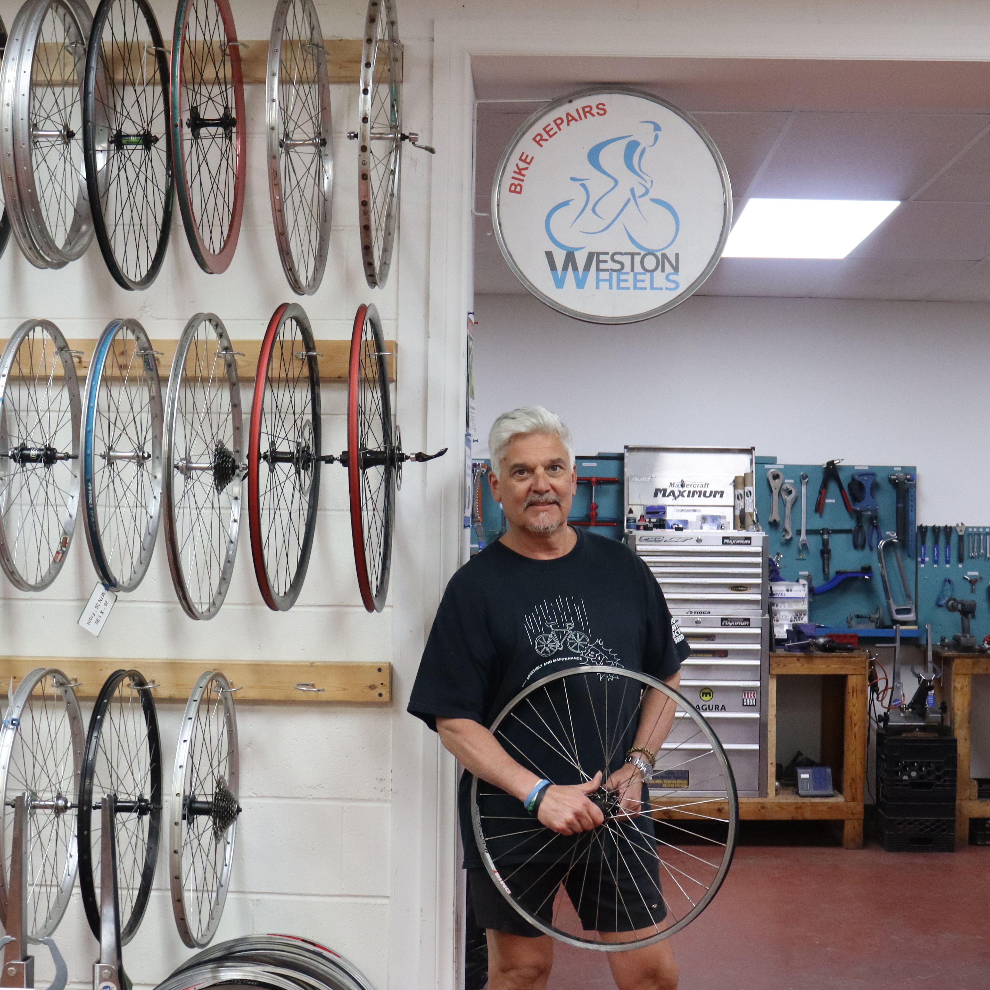 A man standing posing for the camera under the Weston Wheels bike sign.