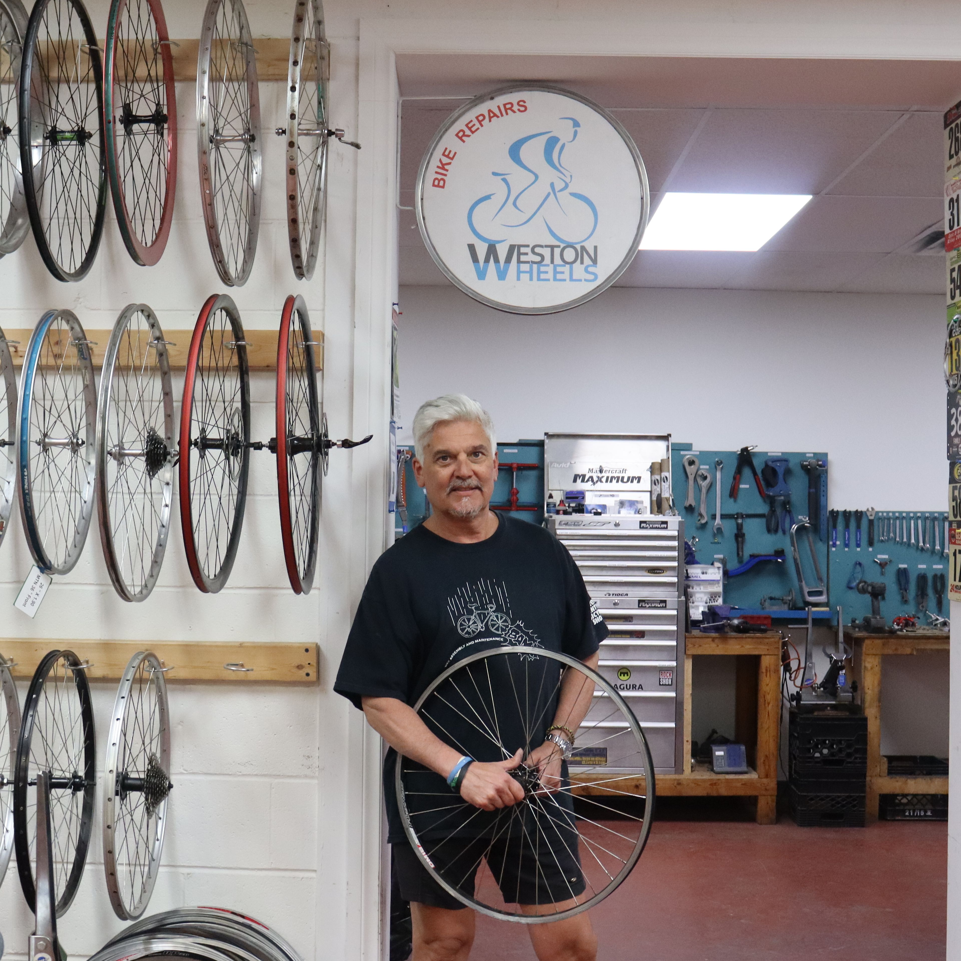 An educator from BAM taking a photo underneath the Weston Wheels bike sign.