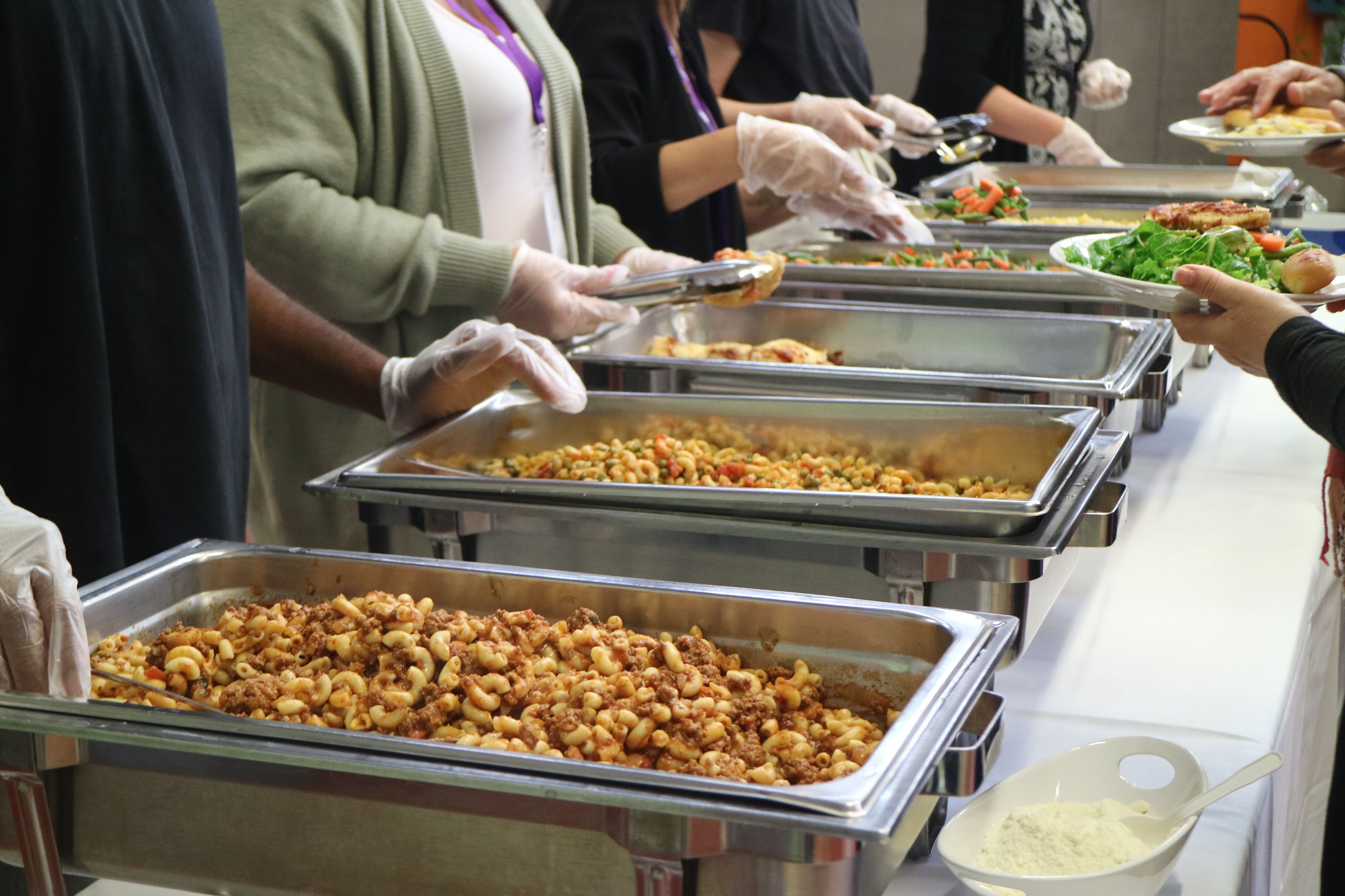 A table of food and people who are serving the food.