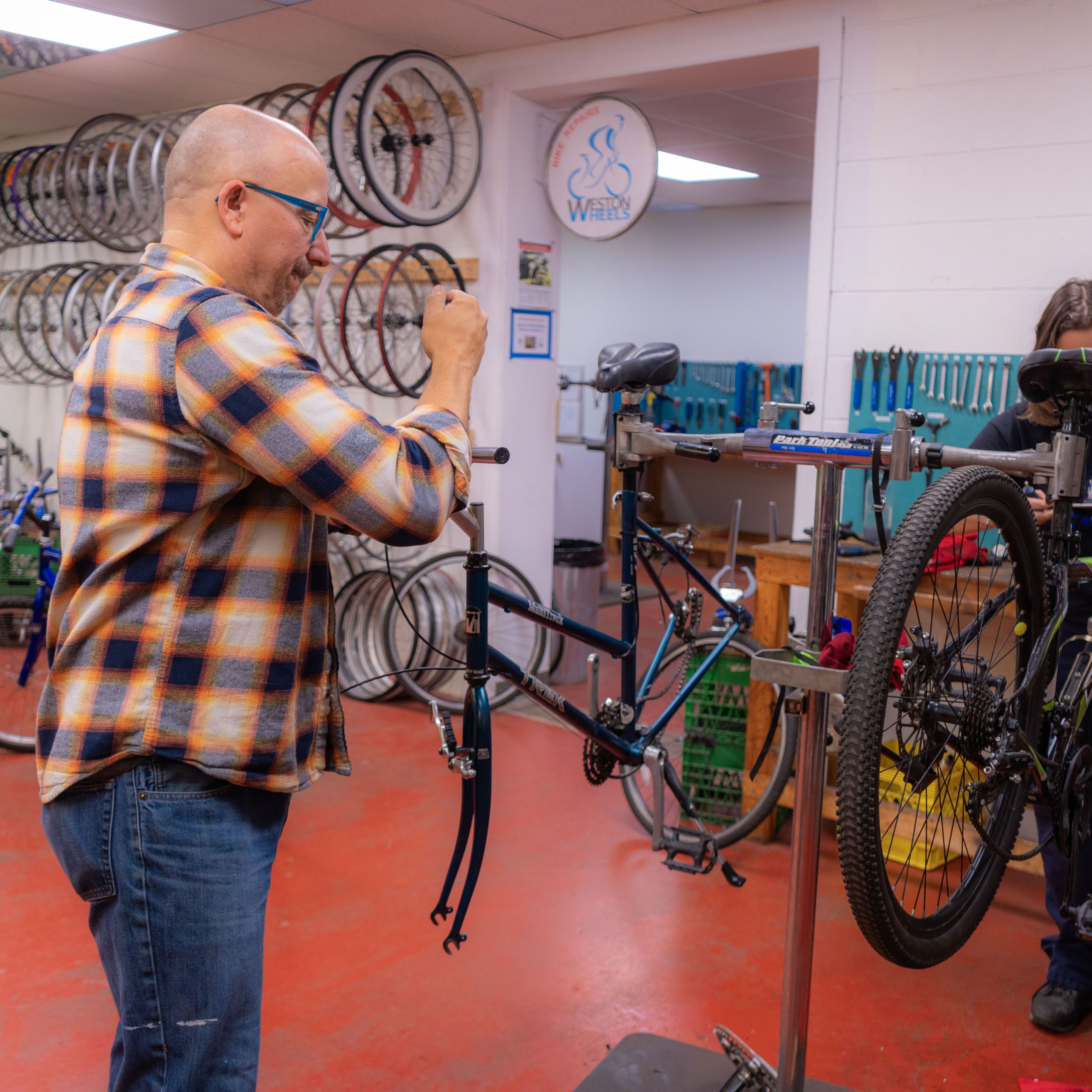 An educator helping a student in BAM fix a bike.