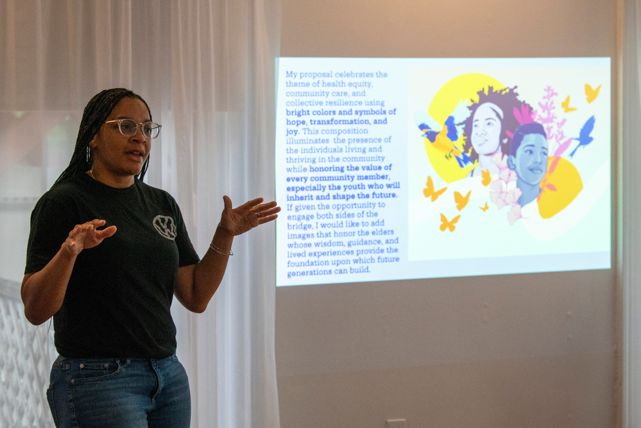 A woman presents a slide featuring colorful illustrations of faces and birds, with text discussing community values and future generations.