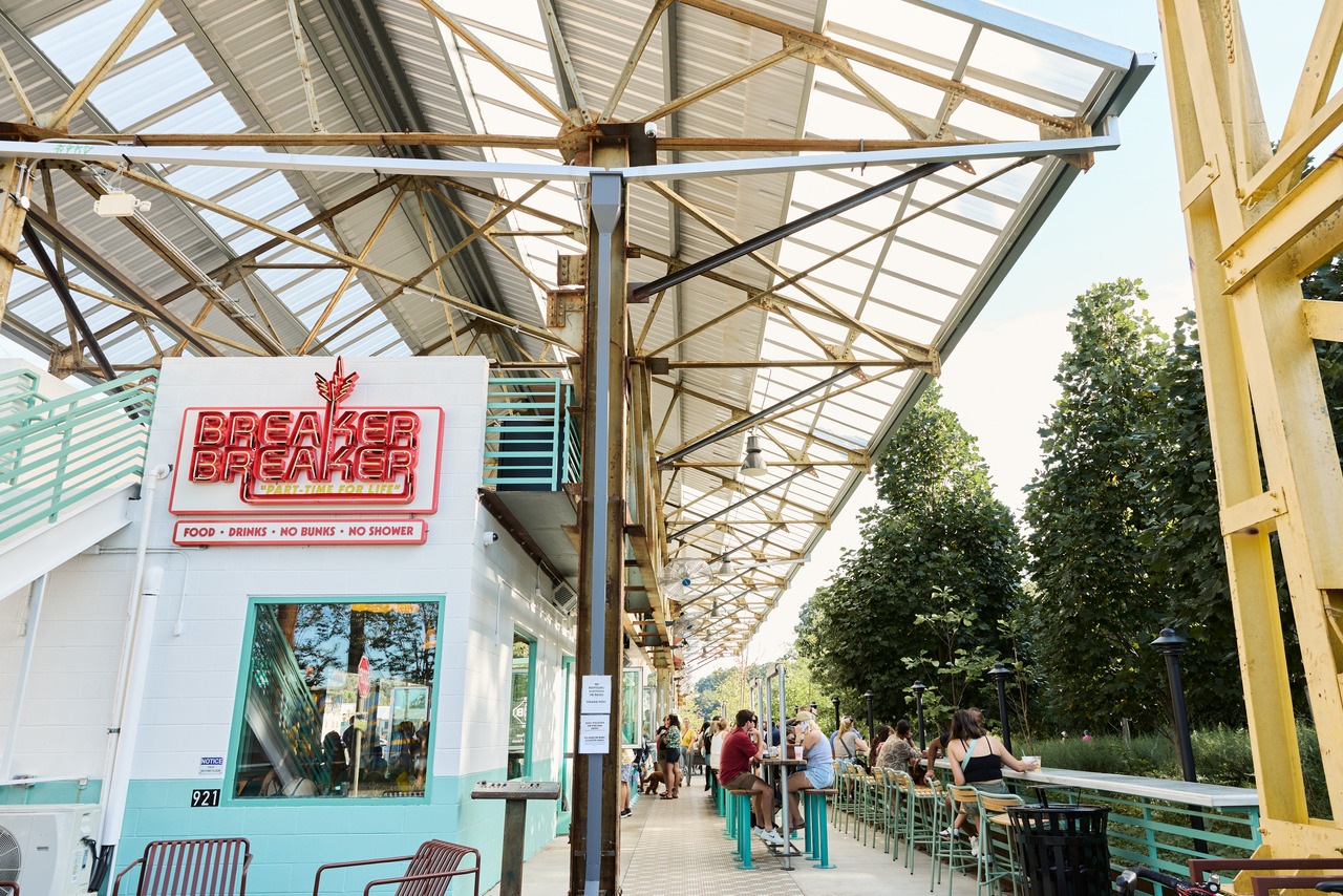 The Southeast Trail has a number of restaurants and shops to explore. (Photo Credit: The Sintoses) Outdoor dining area with people seated at tables under a metal canopy. A sign reads "Breaker Breaker" on a white building. Trees in the background.
