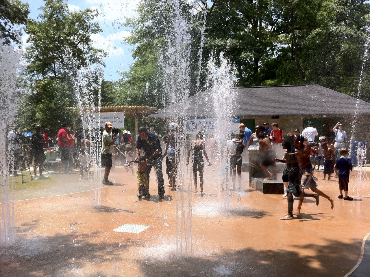 People of all ages laugh and have fun on a large splash pad.