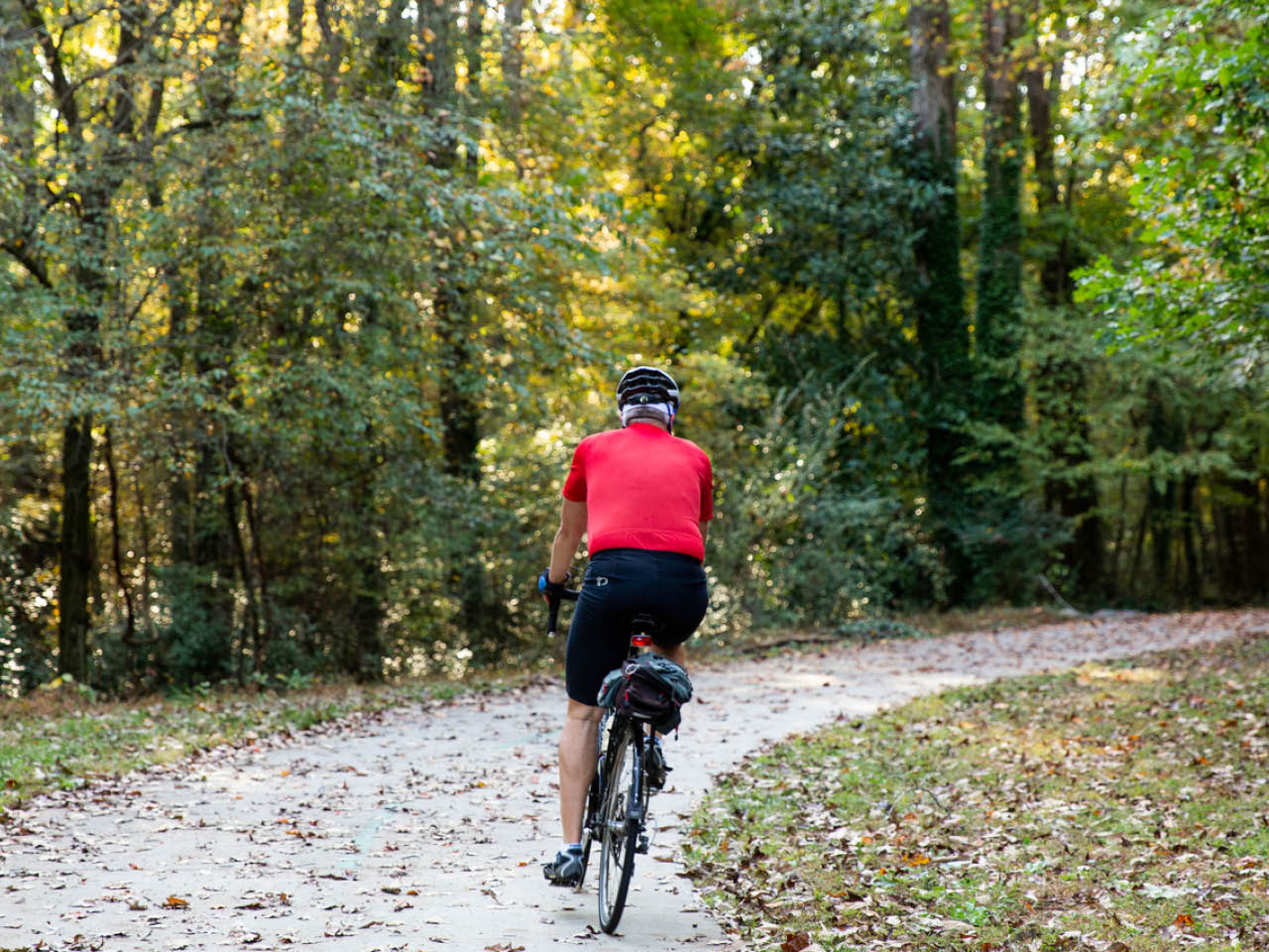 A cyclist rides around a bend through the woods on the Southwest Connector Trail (Photo Credit: Erin Sintos)
