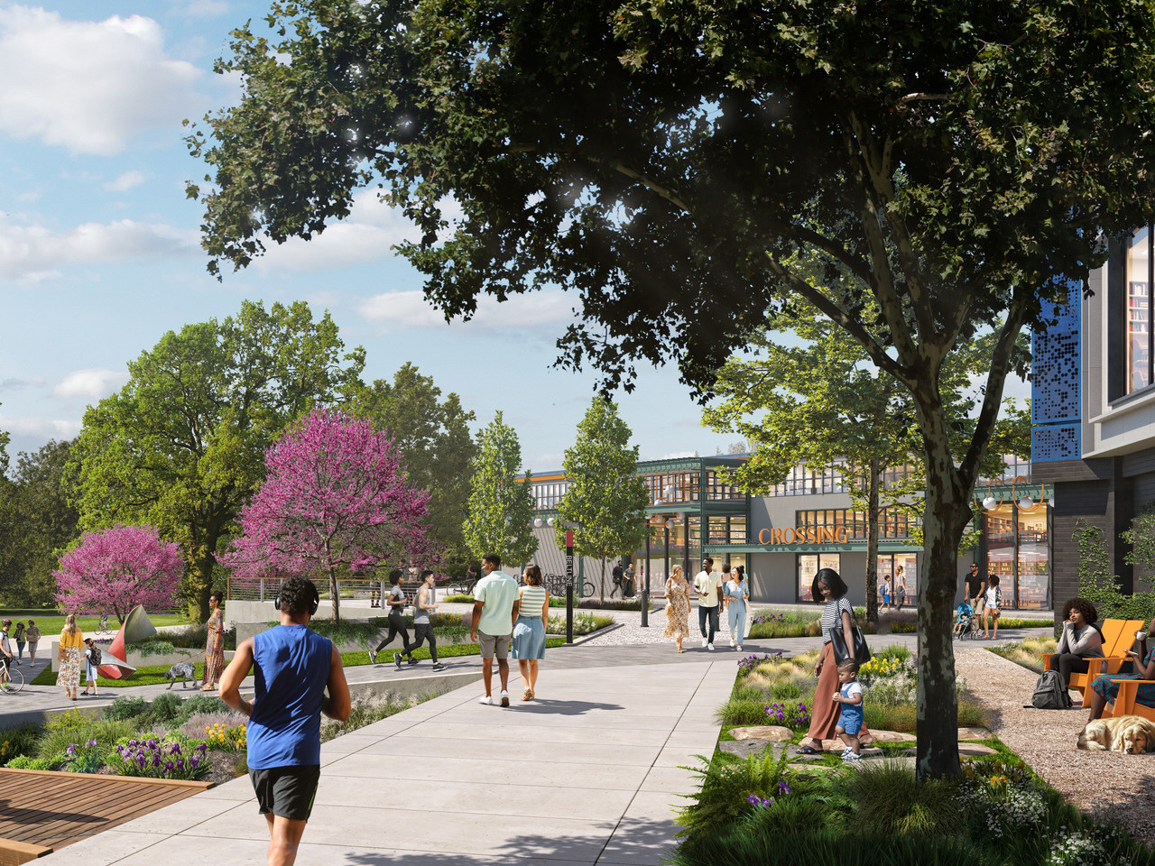 People walking and jogging on a tree-lined path in a modern mixed-use area with greenery and a building in the background.
