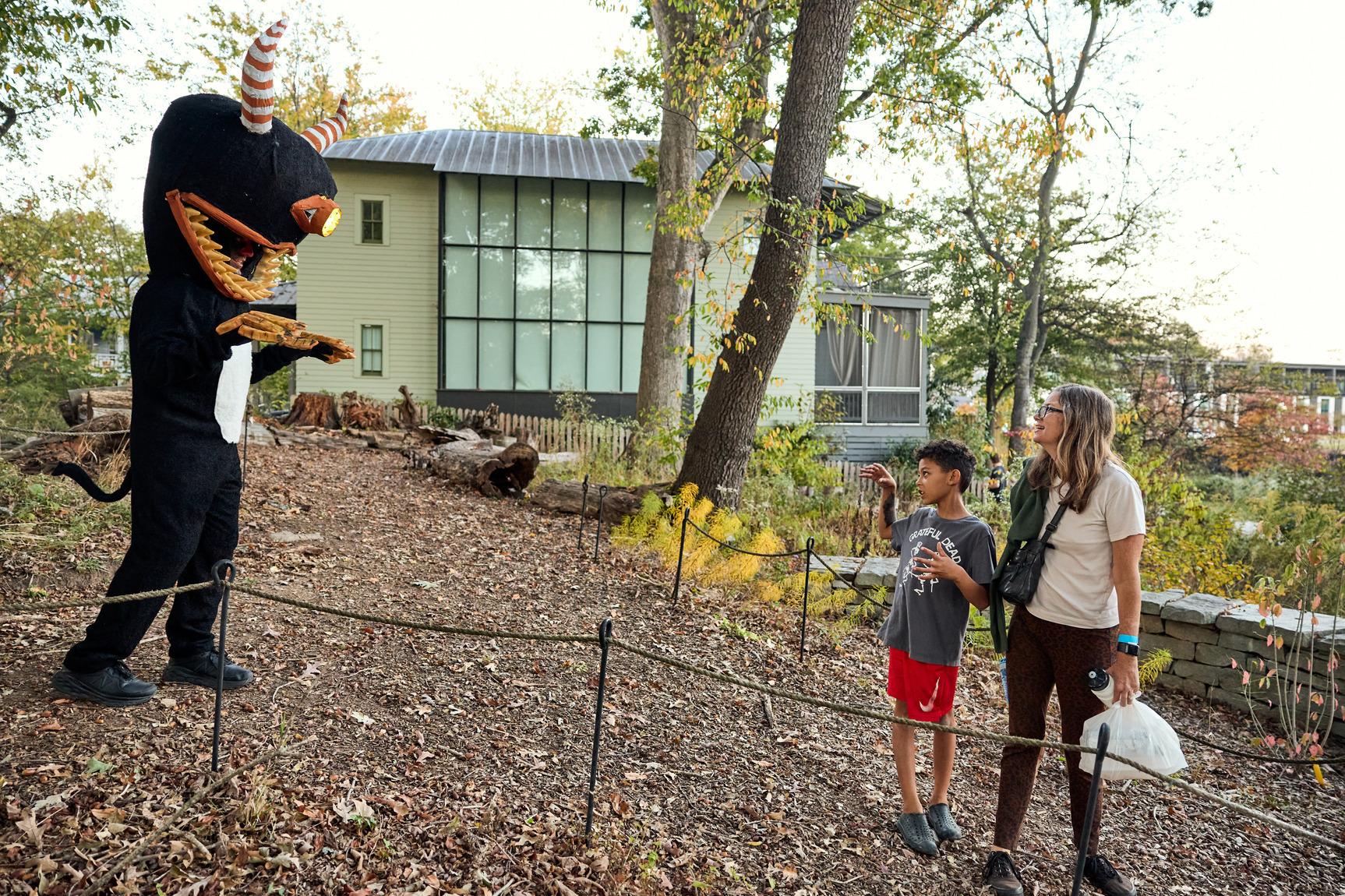 An adult and a young child stand, looking in awe at a cardboard creature.
