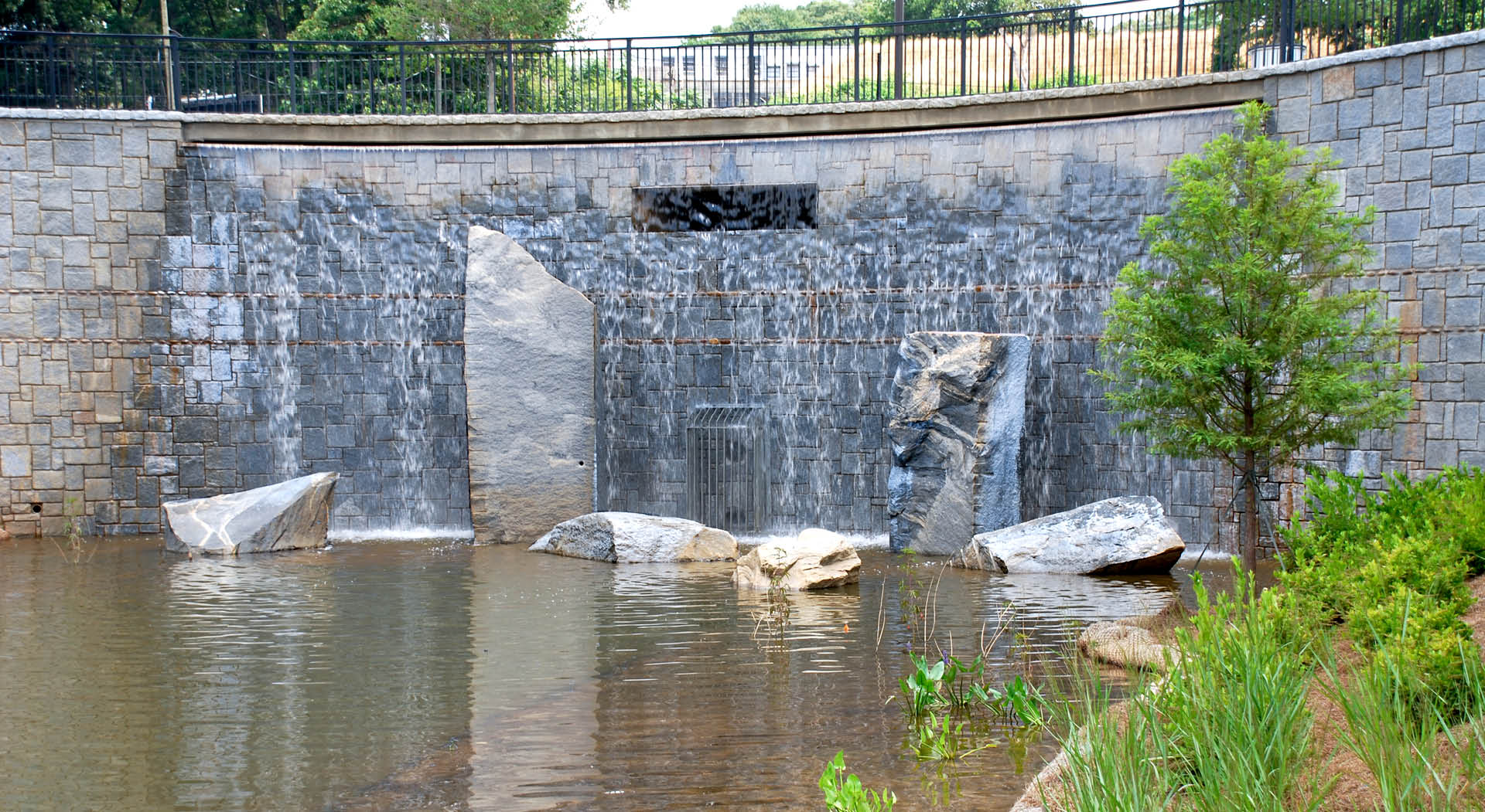Granite wall with waterfall and sculptural boulders.