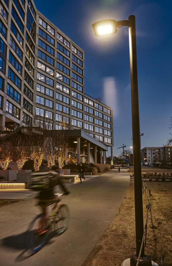 A blurry person bikes past buildings and lights at night.