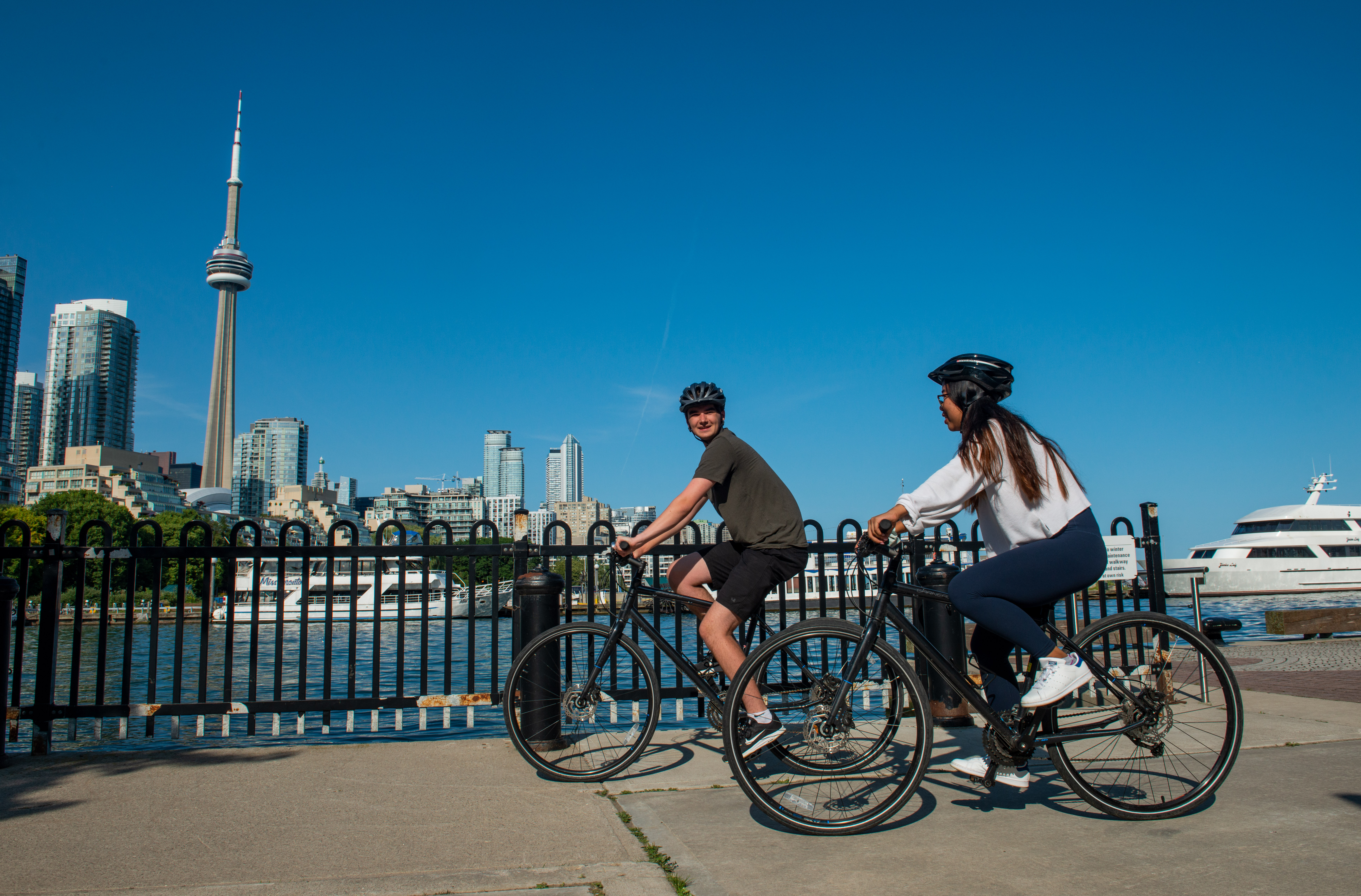 https://a-us.storyblok.com/f/1020317/7017x4623/c87d08ac70/two-people-biking-on-bikes-with-cn-tower.jpg