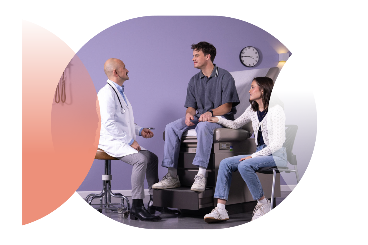internal medicine physician meeting with a man on an exam chair and woman sitting on a chair next him holding his hand