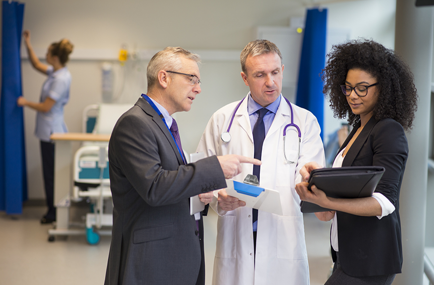 Healthcare administrators talk with a physician in a hospital room