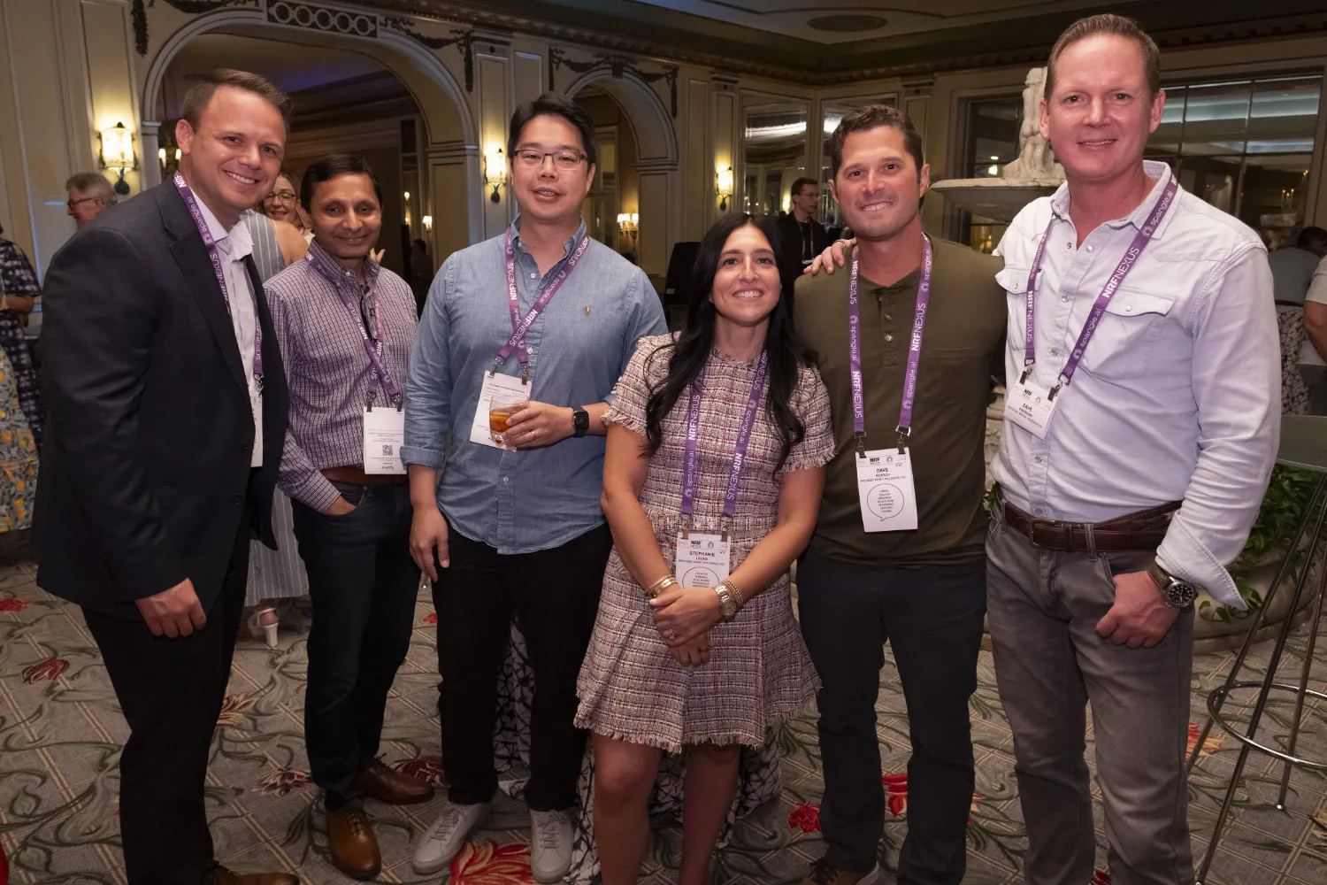Six attendees smile broadly as they pose for a photo at one of the NRF Nexus receptions.