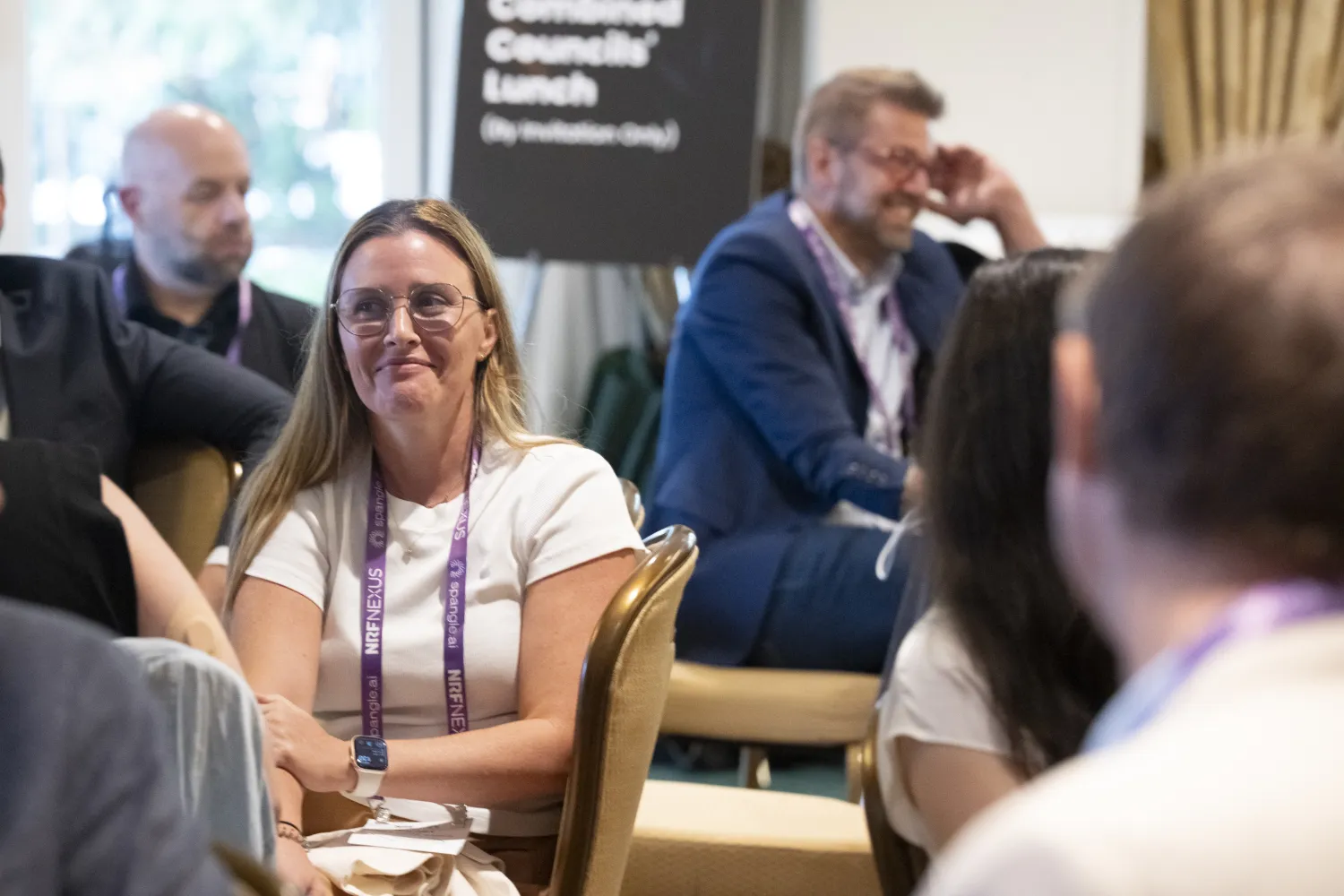 Attendees at NRF Nexus laugh and smirk during the a presentation.