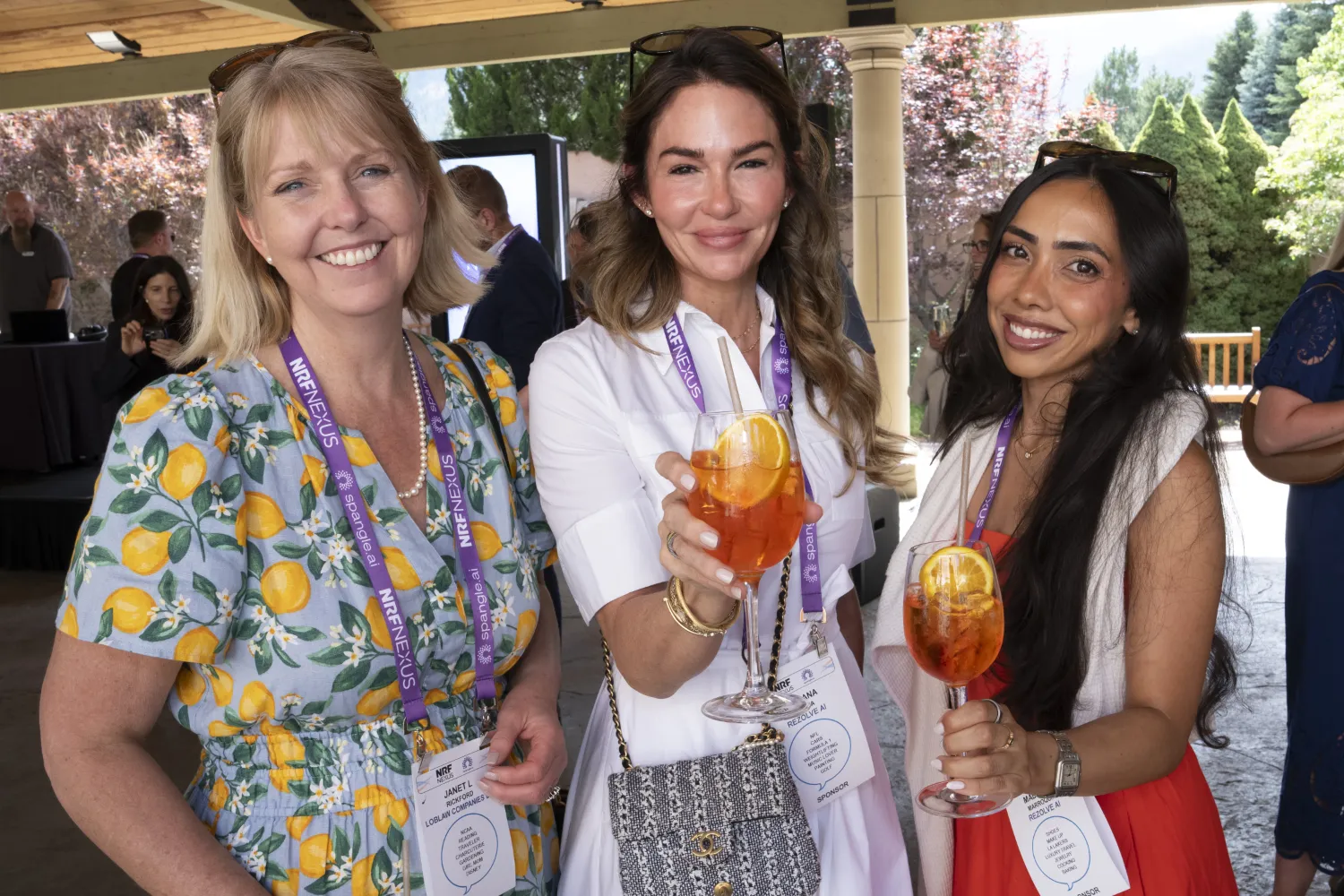 Three women enjoy drinks with orange slices in them during the NRF Nexus welcome reception.