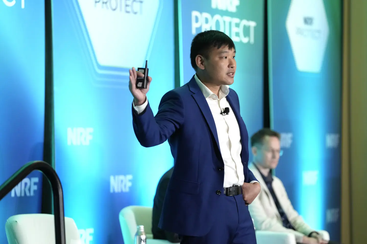 A man in blue suit answers questions from the stage at NRF PROTECT.