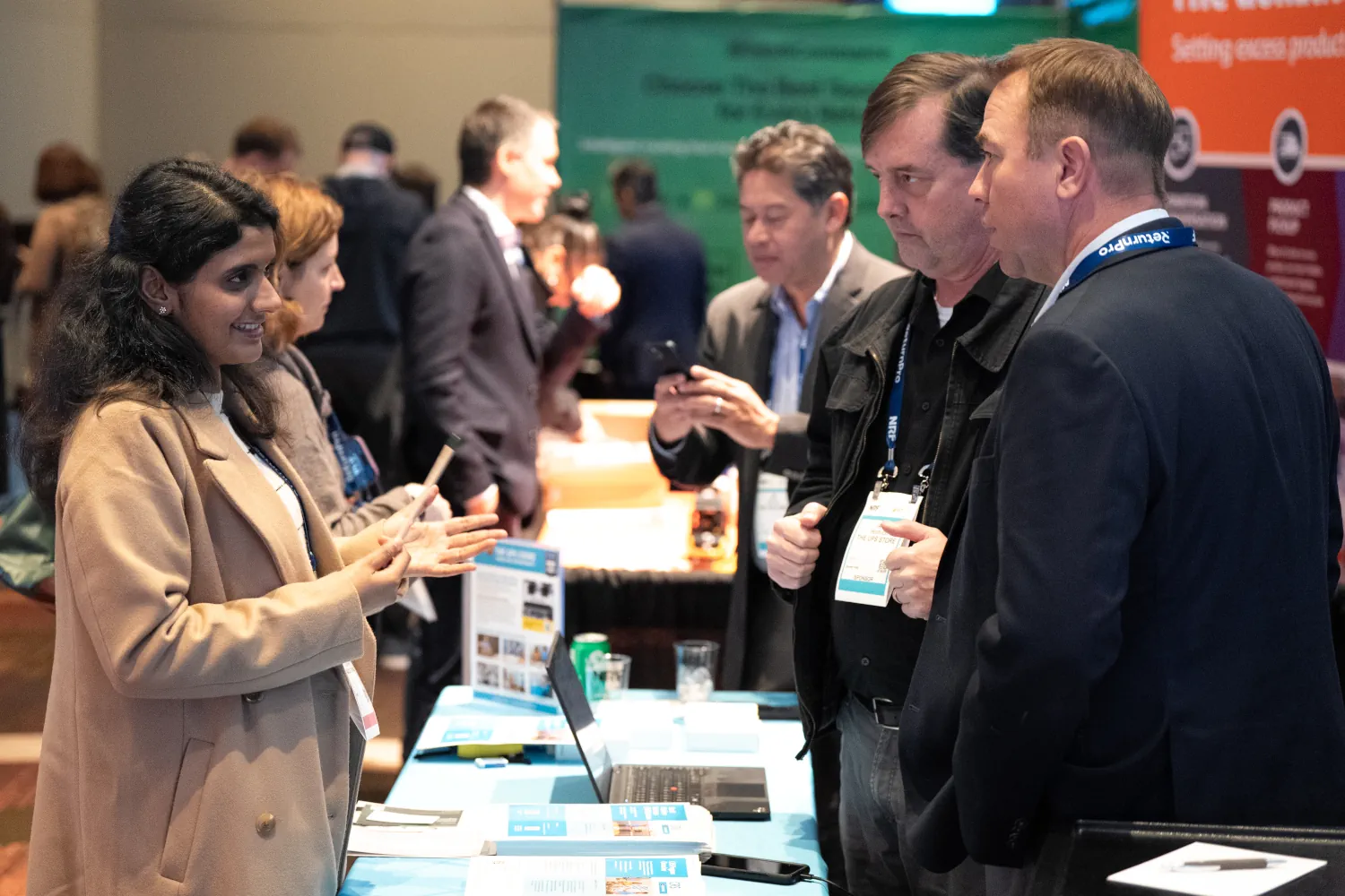 A woman stands at a table in the NRF Expo learning from two technology vendors.