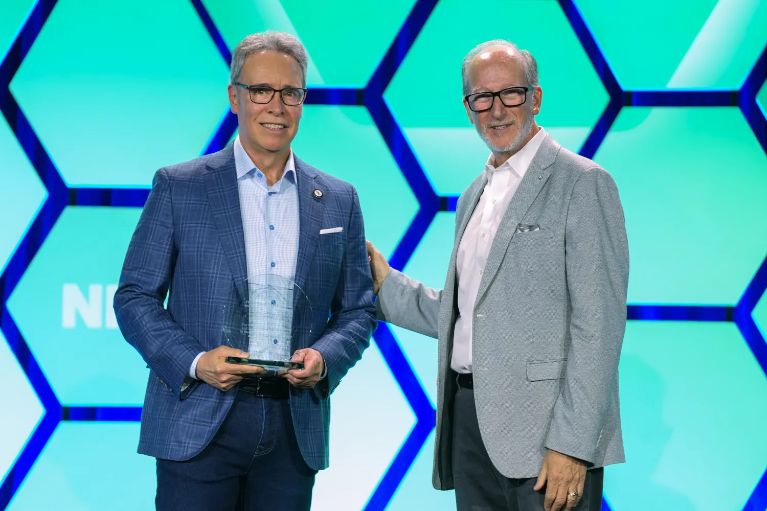 Individual standing on stage holding an award at NRF PROTECT, smiling and posing for photos after the ceremony.