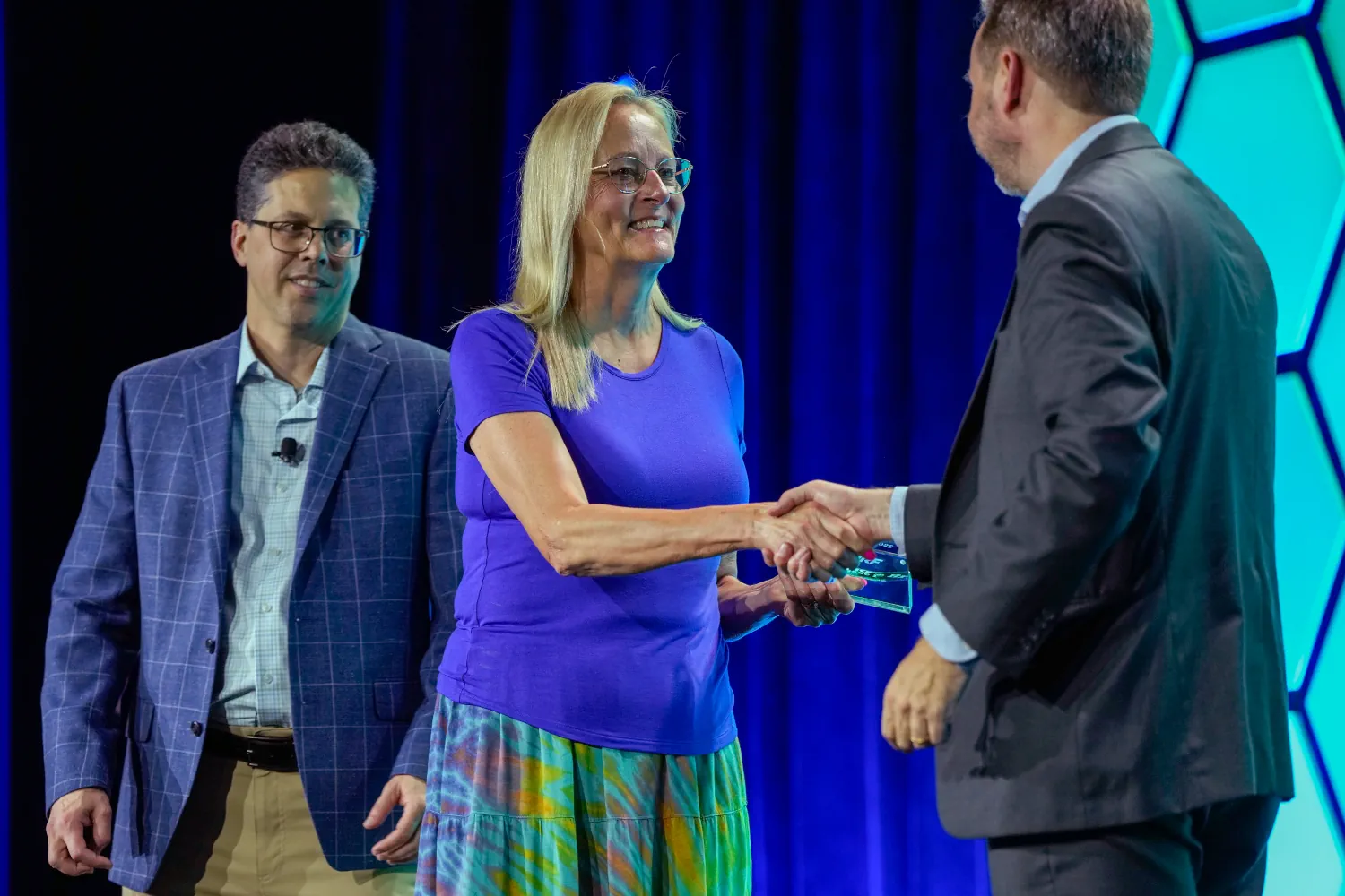 A NRF PROTECT award recipient crosses the stage to accept the award and to shake hands with the presenter.