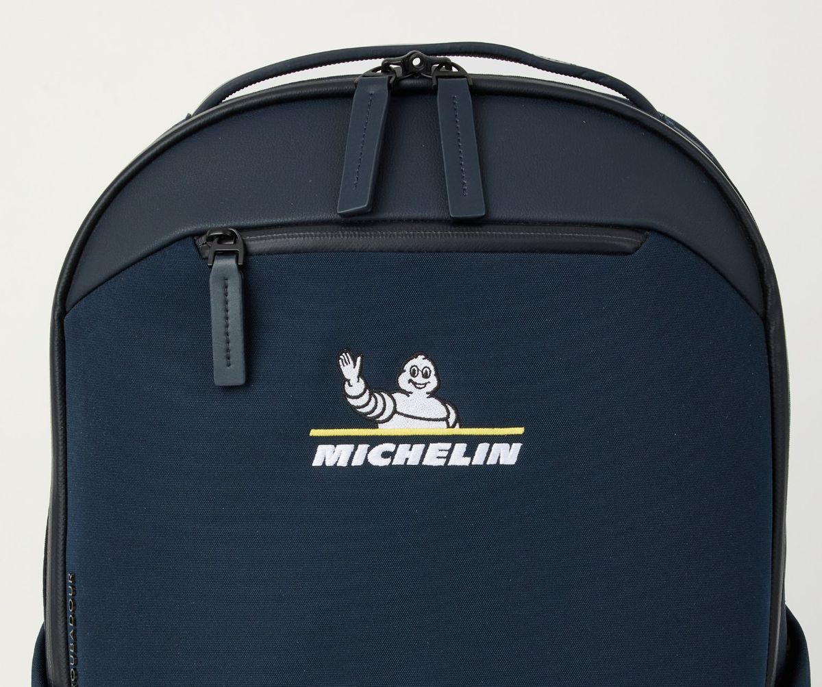 Navy Troubadour Apex Backpack with the Michelin logo embroidered in white and yellow thread on the front panel