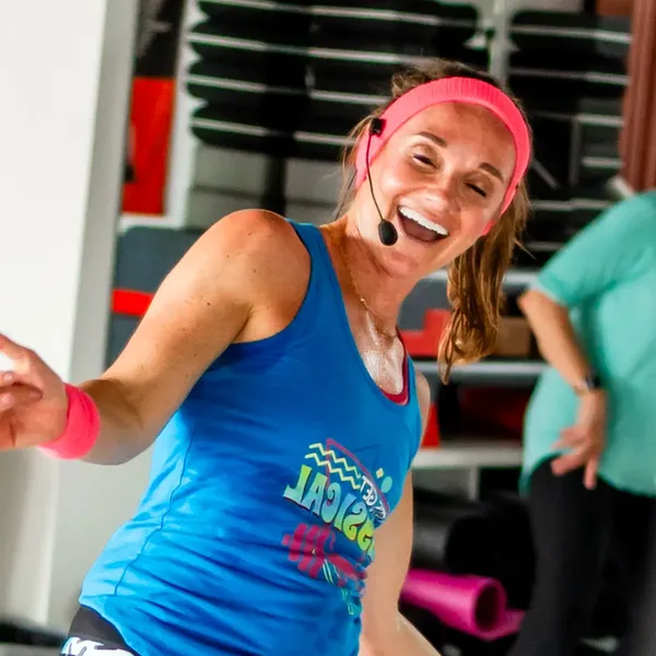 An image of a smiling fitness instructor in a blue tank top and pink headband from welo’s event at Seven Studios.