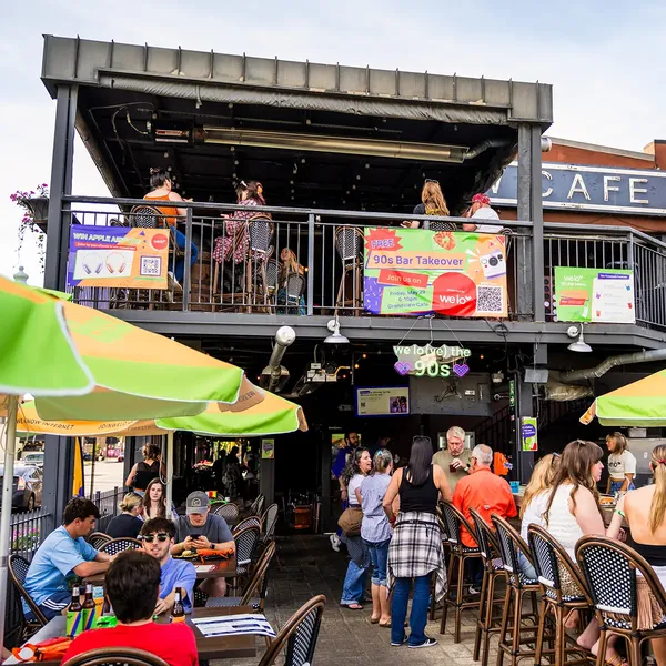 An image of people socializing at Grandview Cafe’s outdoor patio and bar decorated for welo’s 90s bar takeover event.