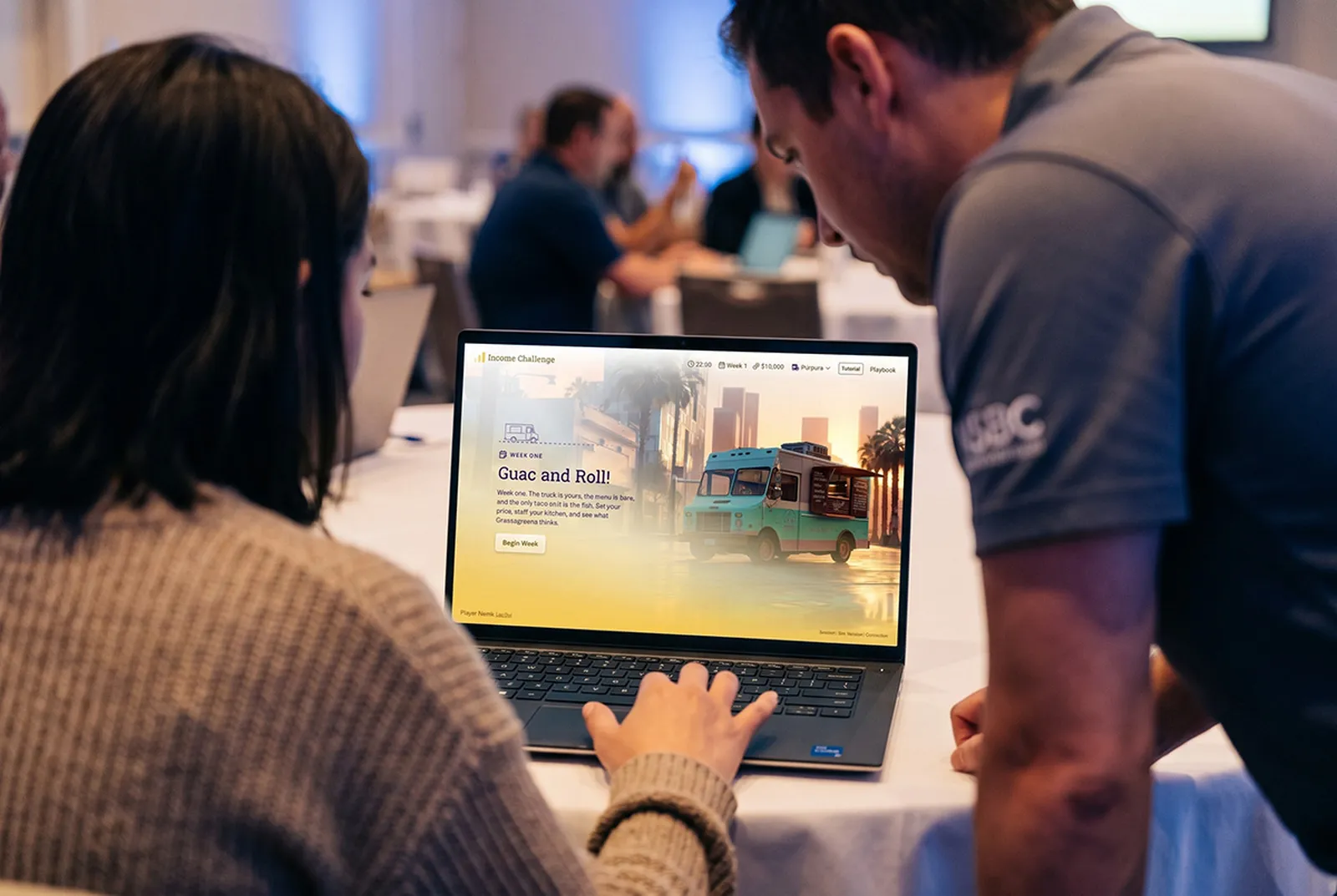 Two leaders playing the Income Challenge simulation on a shared laptop