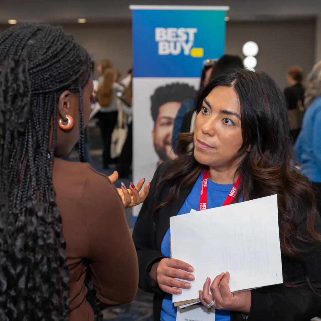 A representative from BEst Buy talks about jobs and internships with a student during a career fair.