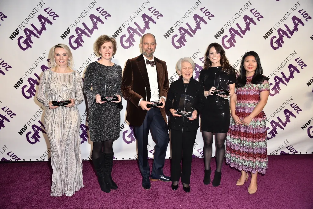 Six NRF Foundation Honors honorees stand in front of step-and-repeat, smiling and holding their awards. (2017)